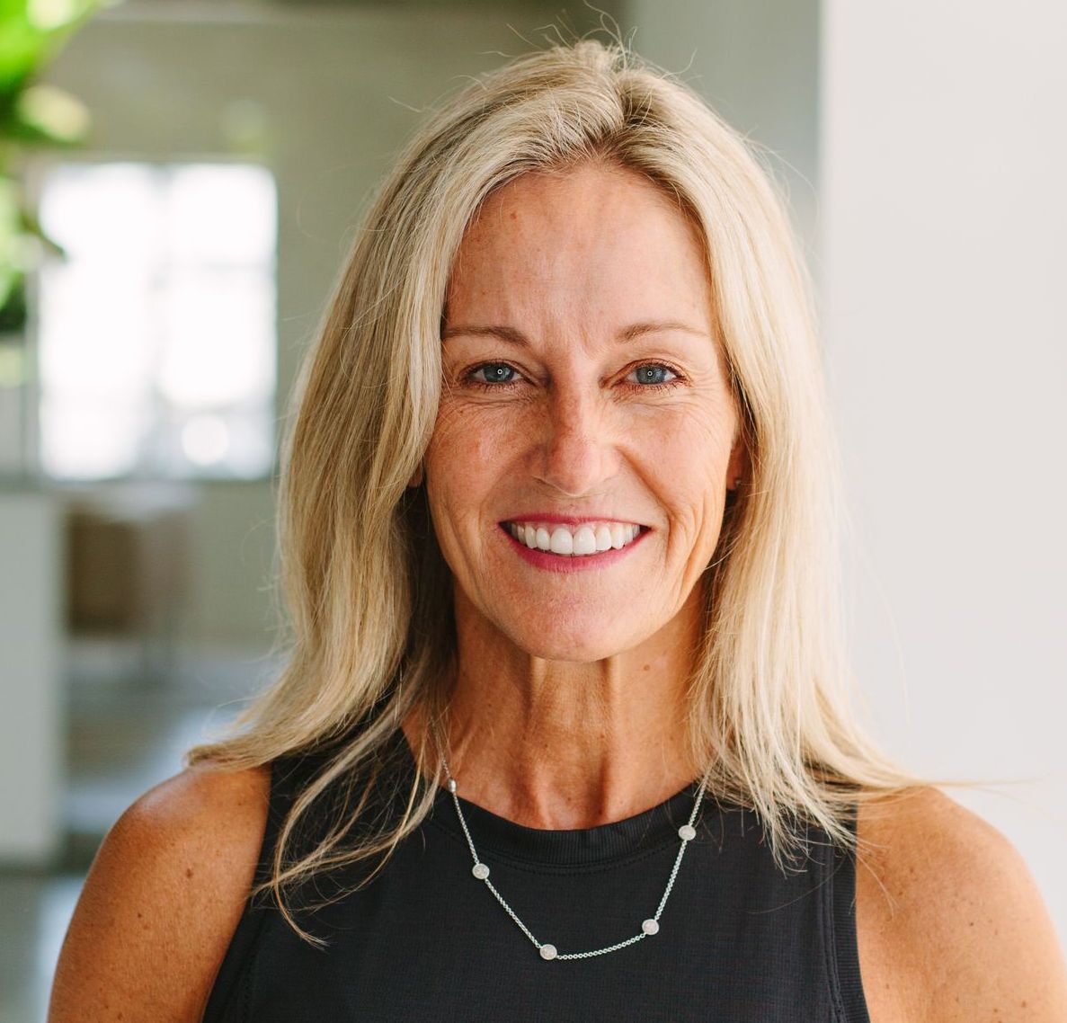 Teacher - Melissa Cejda
Blond woman with a bright smile, wearing a black top and silver necklace, inside a well-lit home.