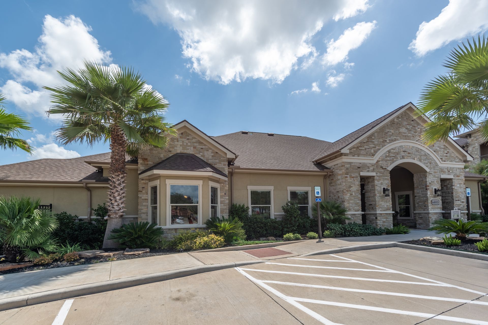 A large apartment leasing building with a parking lot in front of it at Marquis Seven Lakes offers apartments in Katy, TX.
