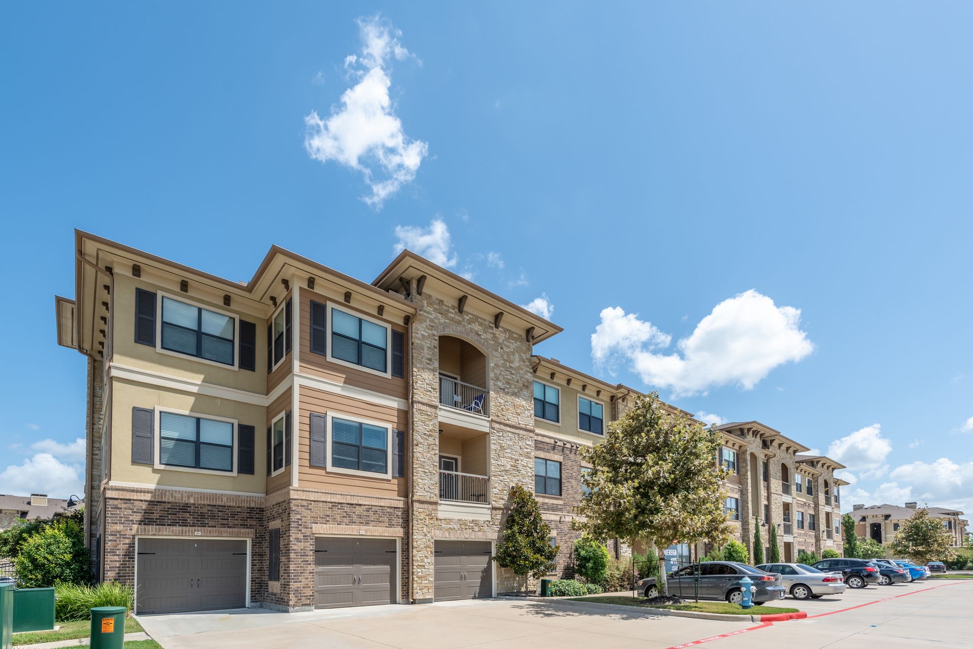 A large apartment building with a lot of cars parked in front of it at Marquis Seven Lakes offers apartments for rent in Katy, TX.