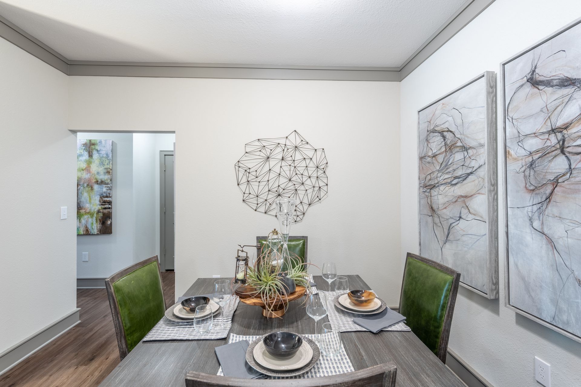 A dining room with a table and chairs and paintings on the wall at Marquis Seven Lakes offers apartments for rent in Katy, TX.
