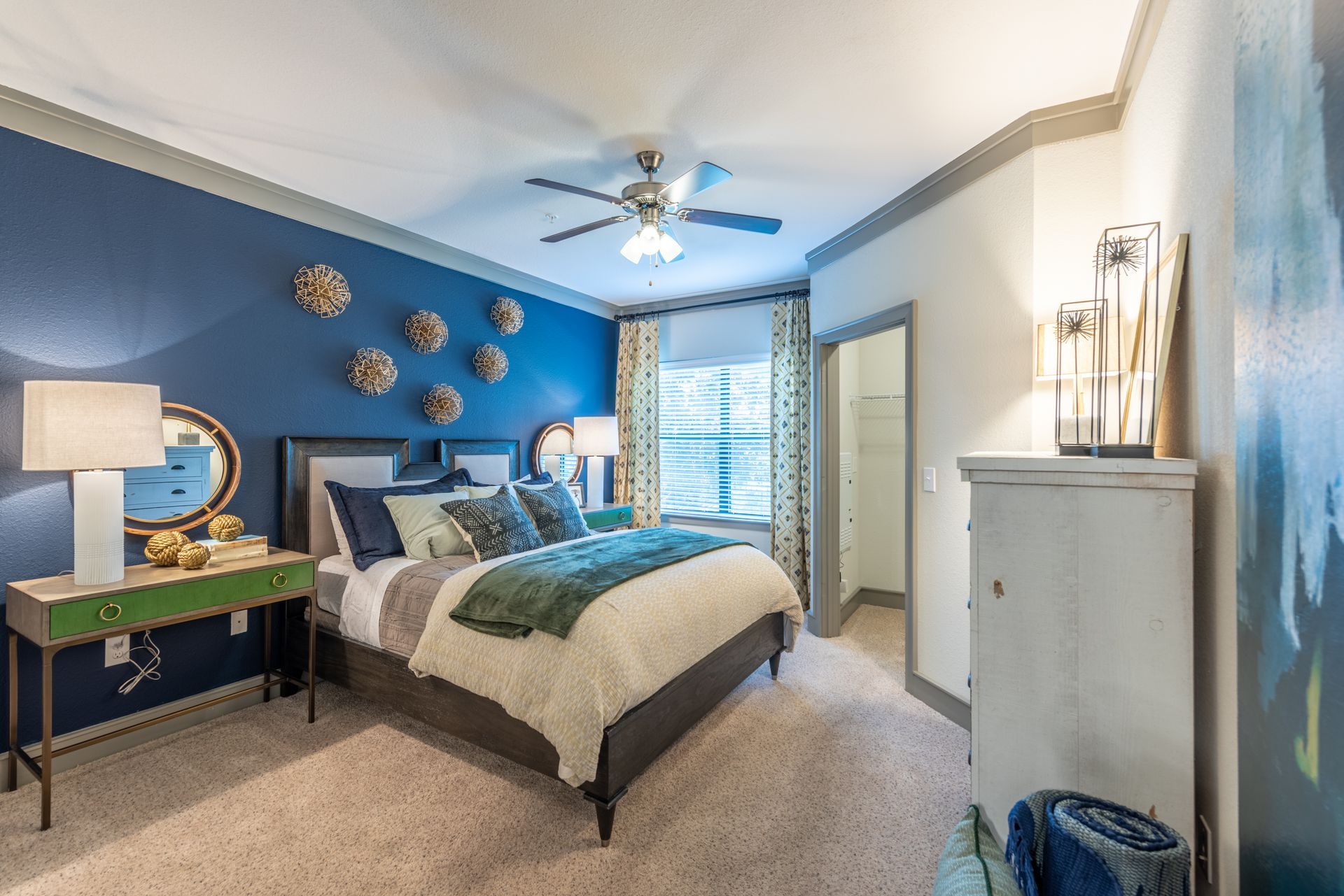 A bedroom with a bed, dresser, mirror and ceiling fan at Marquis Seven Lakes offers apartments for rent near Cinco Ranch, TX.