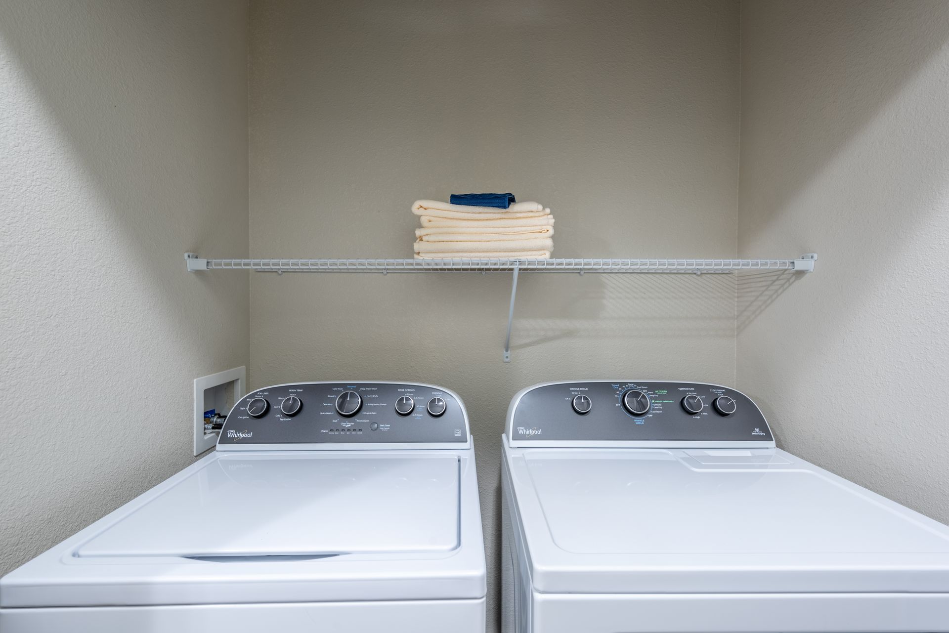 Two white washers and dryers are in a laundry room at Marquis Seven Lakes offers apartments in Katy, TX.