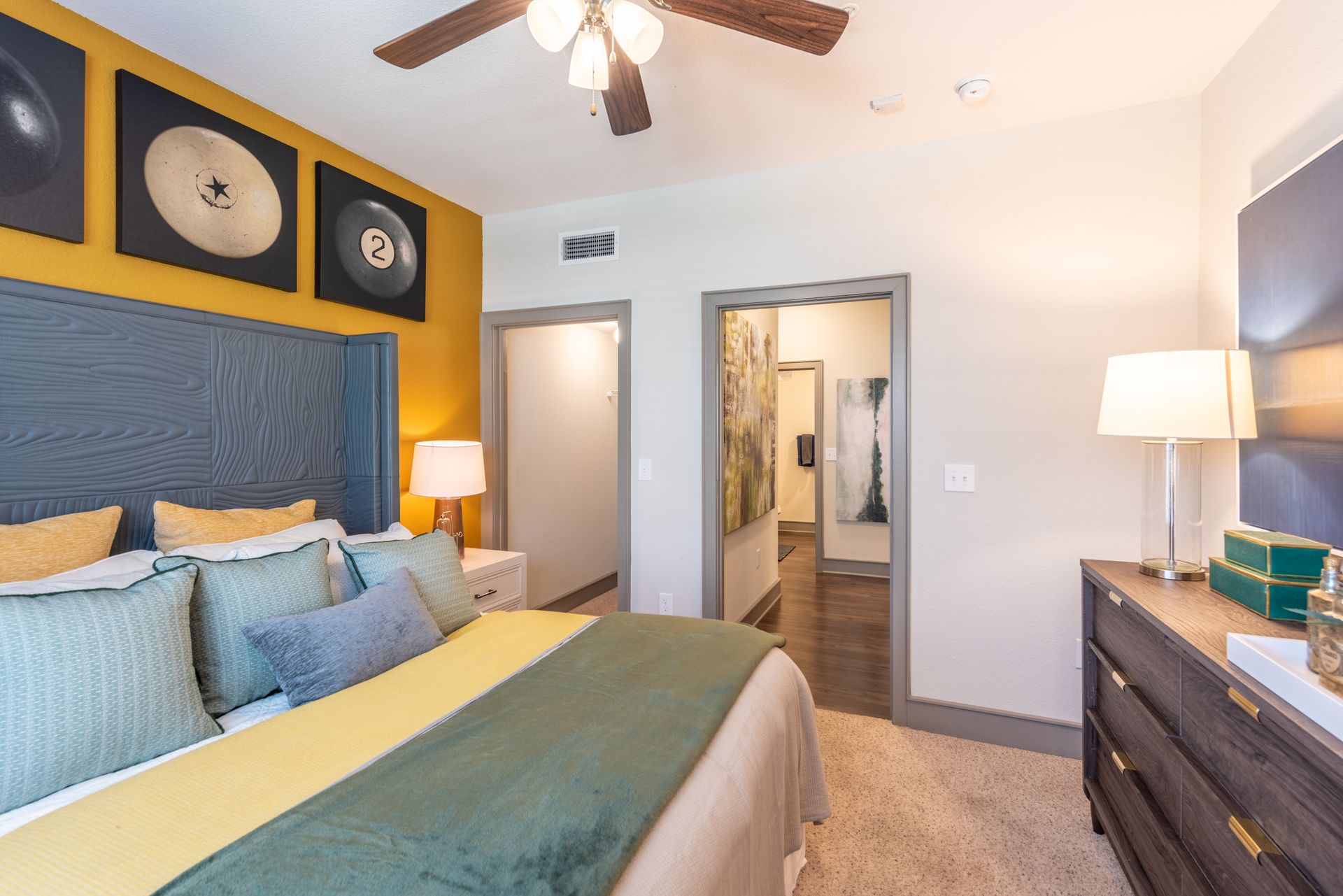A bedroom with a bed, dresser, lamp and ceiling fan at Marquis Seven Lakes offers apartments near Cinco Ranch, TX.