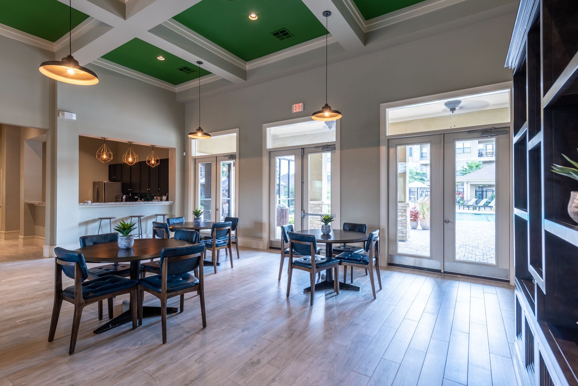 A large room with tables and chairs and a green ceiling at Marquis Seven Lakes offers Katy apartments for rent.