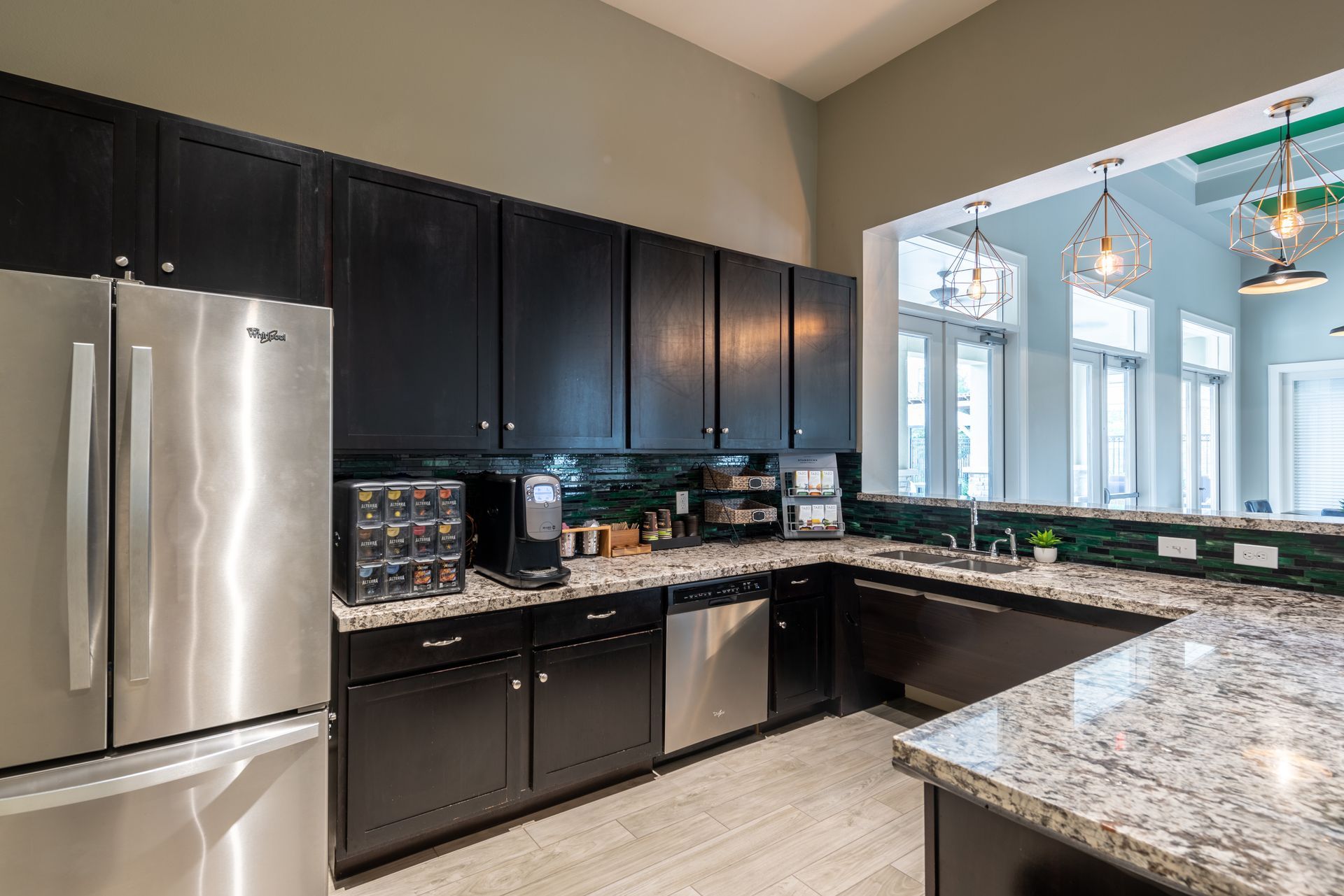 Apartment community kitchen with dark cabinets, stainless steel appliances, granite counter tops and a refrigerator at Marquis Seven Lakes offers apartments for rent in Katy, TX.