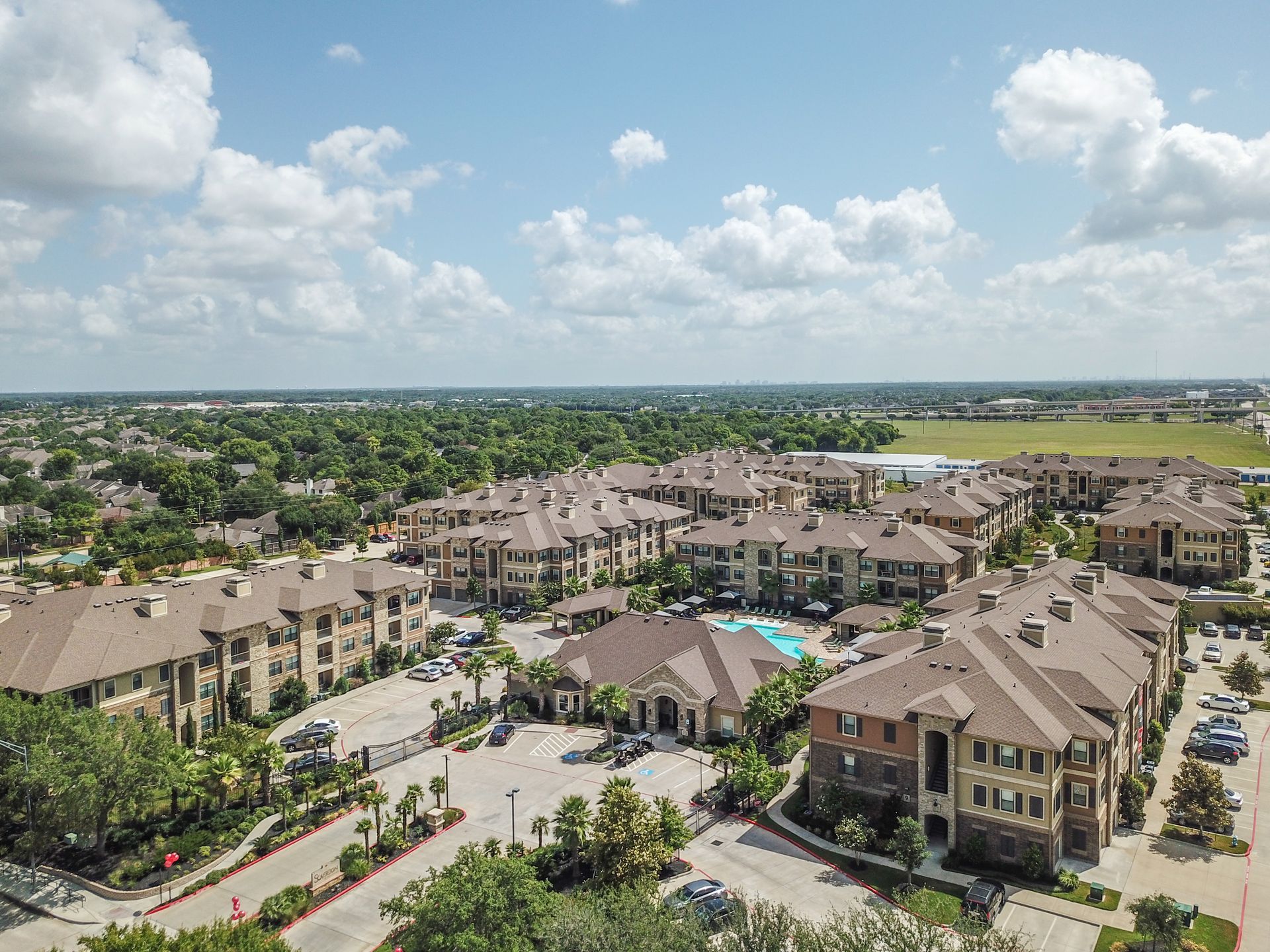 An aerial view of a large apartment complex with a pool in the middle at Marquis Seven Lakes offers apartments for rent in Cinco Ranch in Katy, TX.