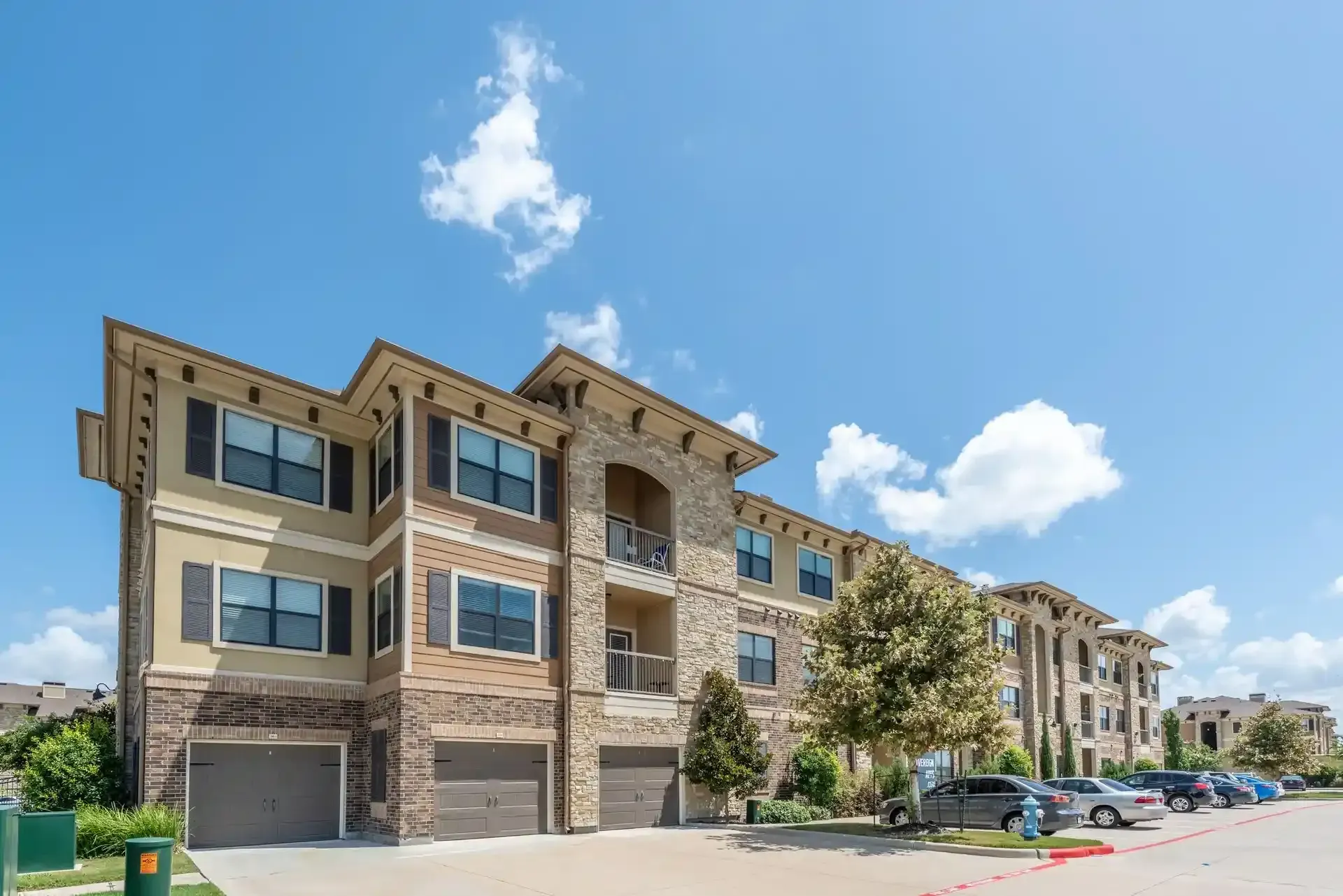 A large apartment building with a lot of cars parked in front of it at Marquis Seven Lakes offers apartments for rent in Katy, TX.