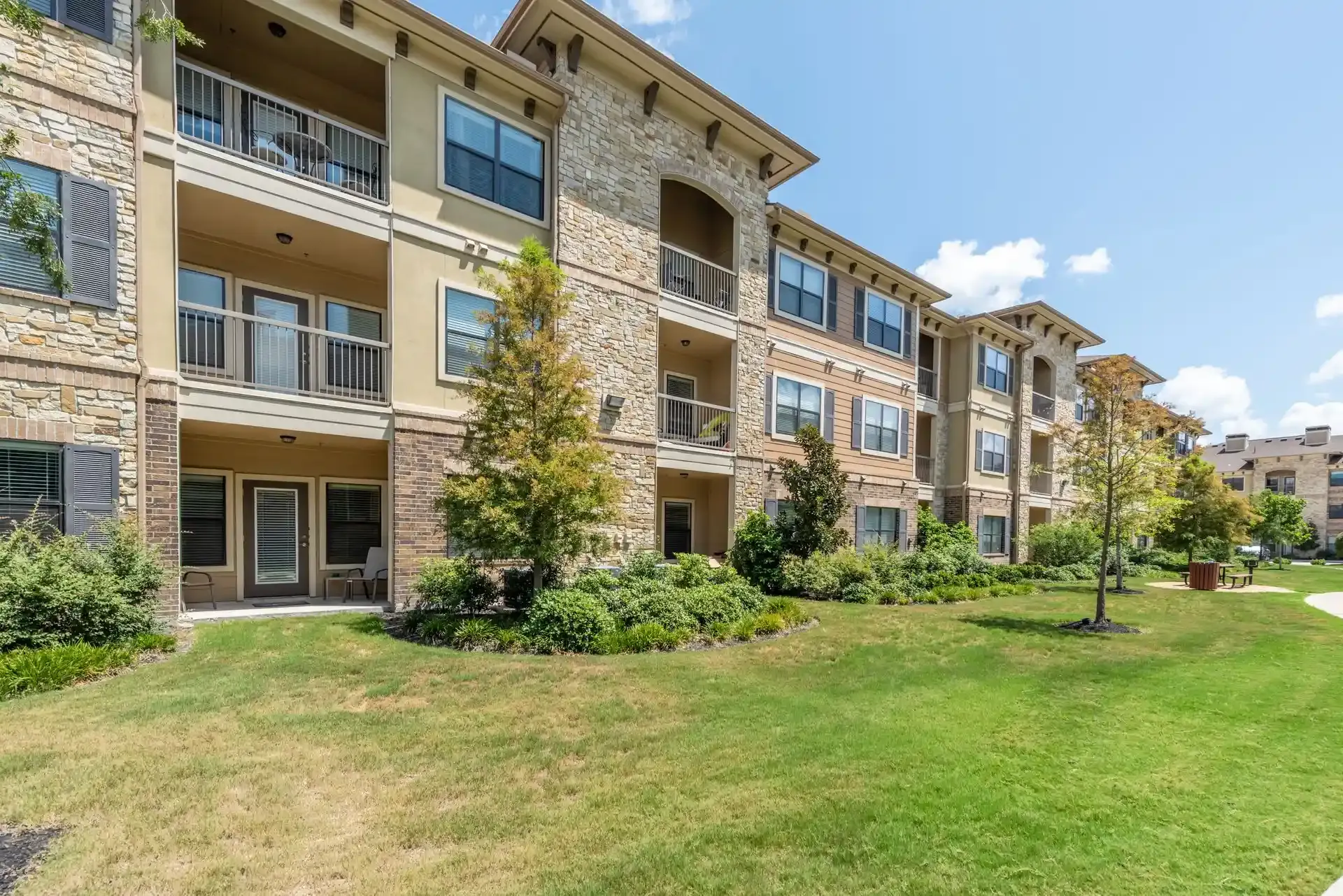 A large apartment building with a lush green lawn in front of it at Marquis Seven Lakes offers pet-friendly apartments for rent in Katy, TX.