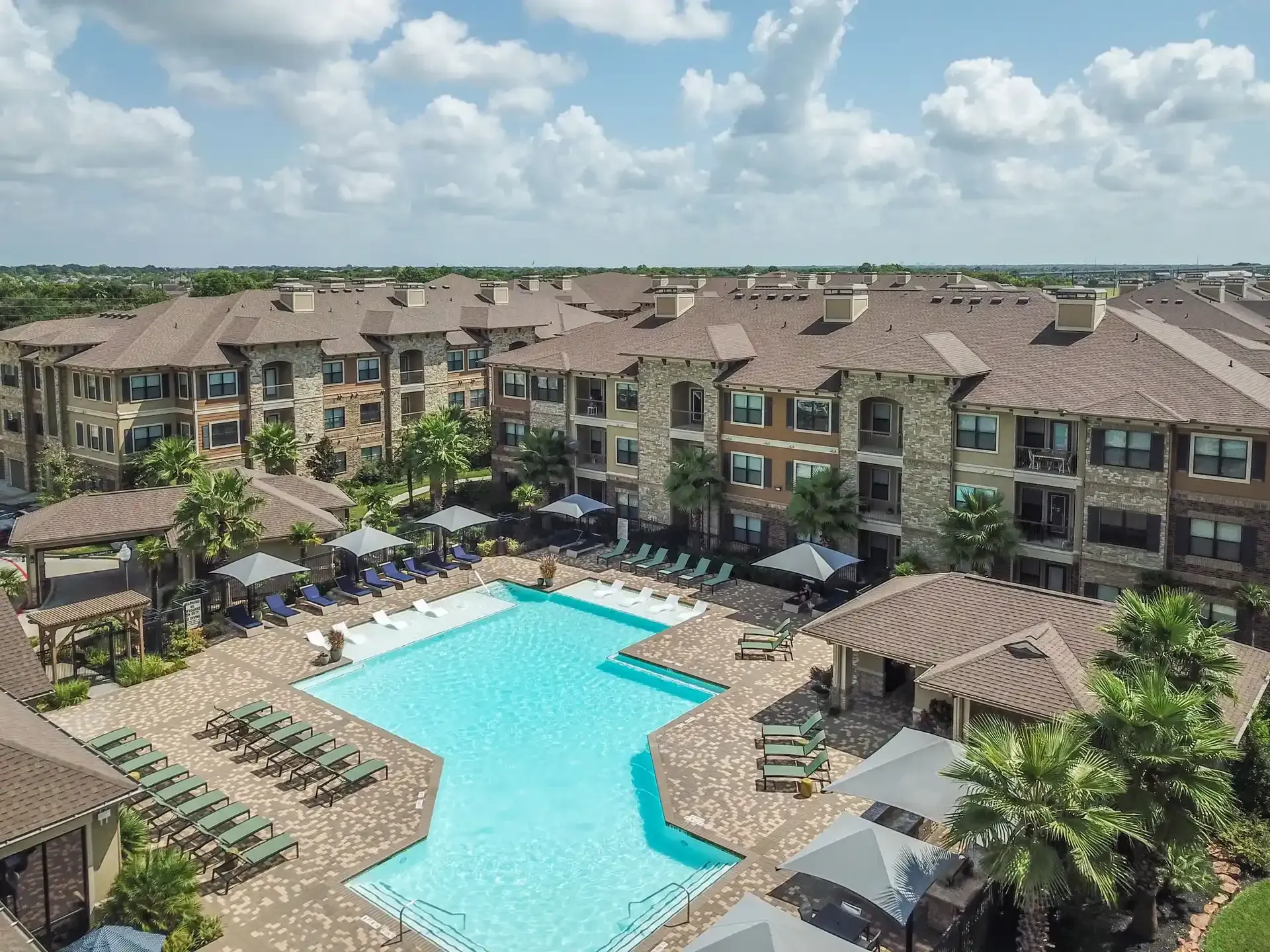 An aerial view of a large swimming pool surrounded by buildings at Marquis Seven Lakes offers apartments for rent near LaCenterra at Cinco Ranch.