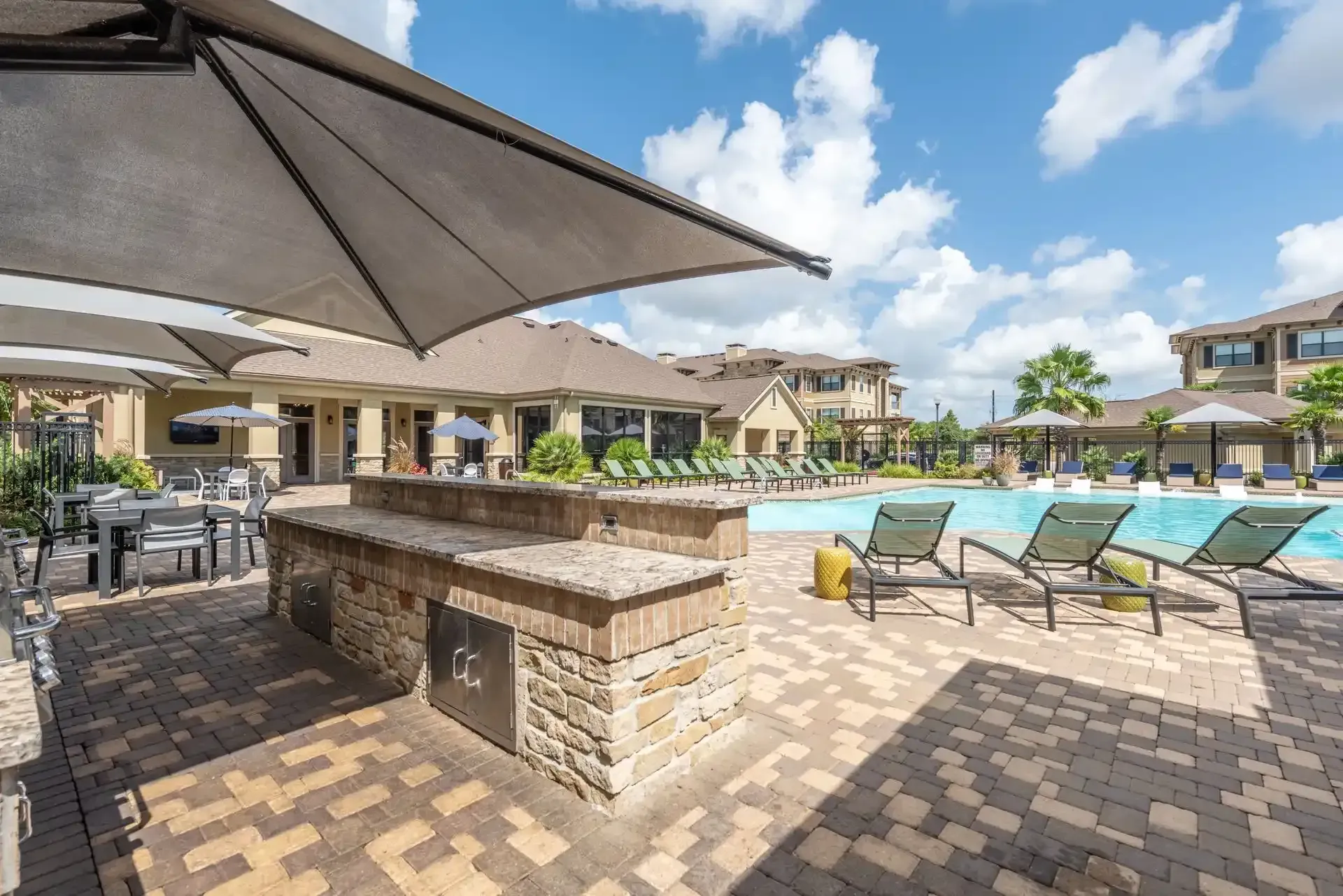A large swimming pool with umbrellas and chairs around it at Marquis Seven Lakes offers apartments for rent in Katy, TX.