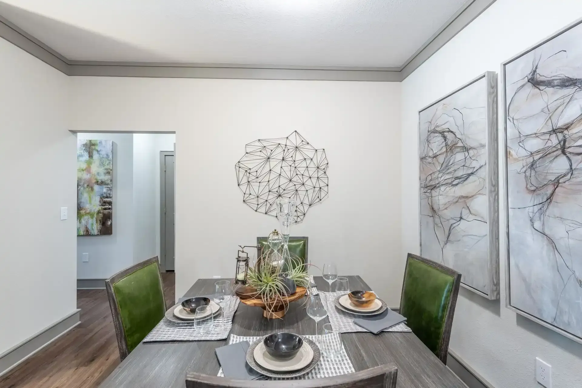 A dining room with a table and chairs and paintings on the wall at Marquis Seven Lakes offers apartments for rent in Katy, TX.