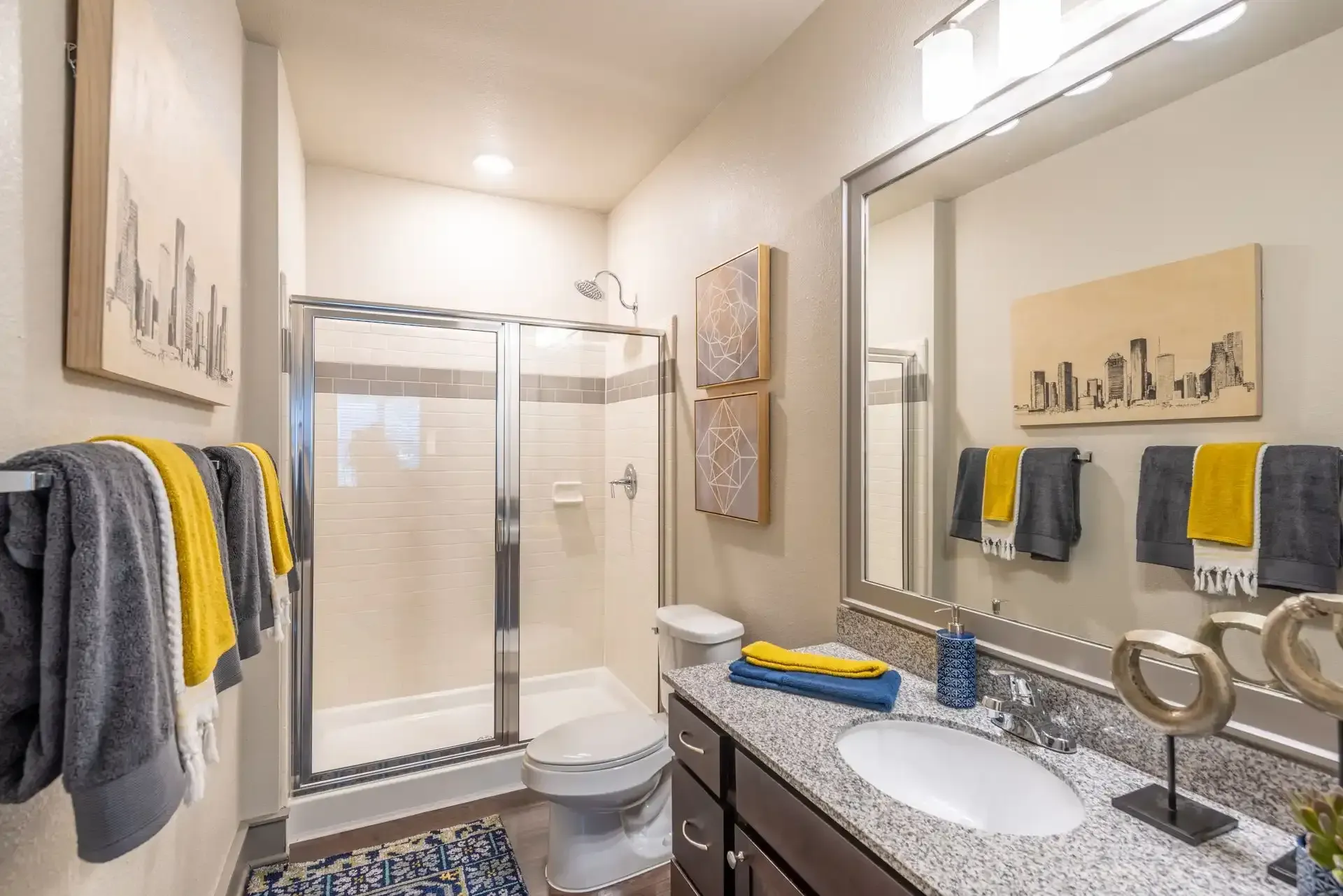 A bathroom with a sink, toilet, shower and mirror at Marquis Seven Lakes offers apartments for rent near Cinco Ranch, TX.