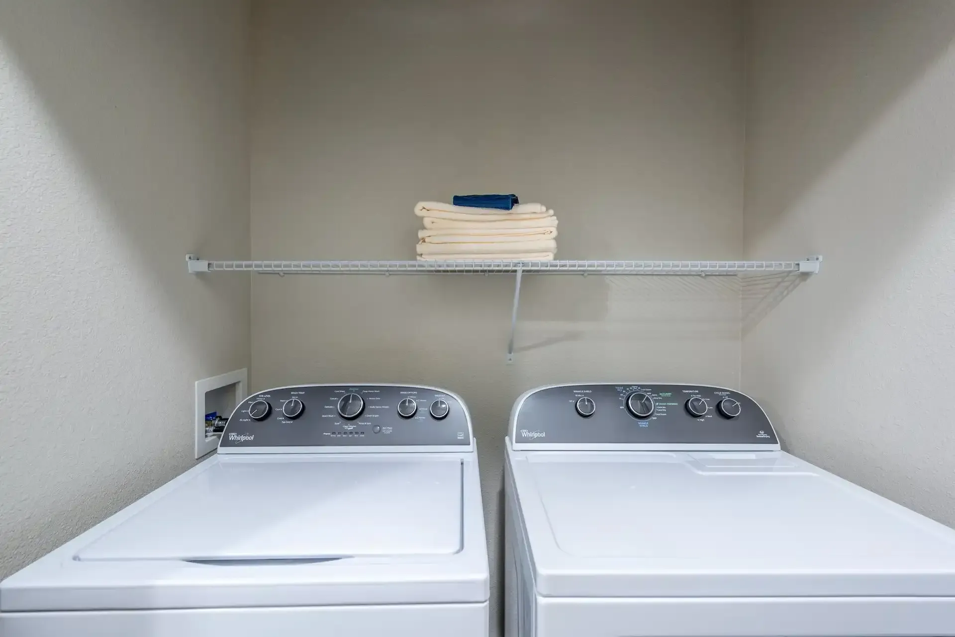 Two white washers and dryers are in a laundry room at Marquis Seven Lakes offers apartments in Katy, TX.