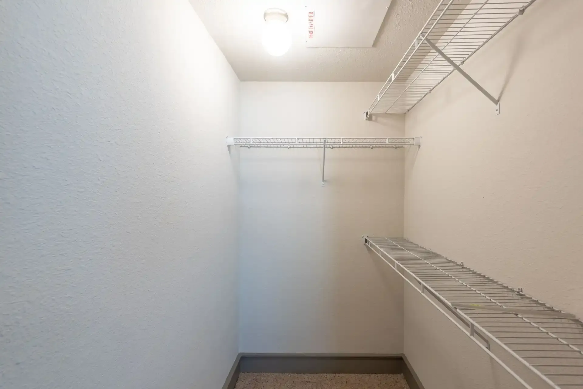 An empty walk in closet with shelves and a light on the ceiling at Marquis Seven Lakes offers pet-friendly Katy apartments for rent in TX.