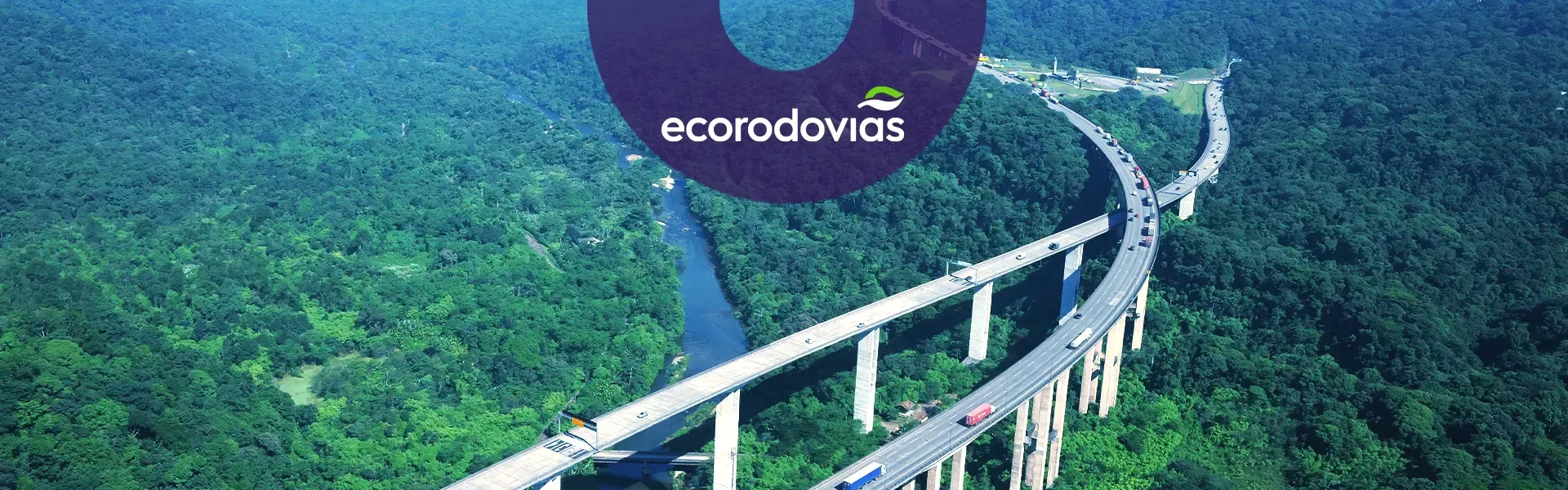 Vista aérea da Rodovia dos Imigrantes, mostrando uma ponte  sobre um rio cercada por árvores, com logo da Ecovias.