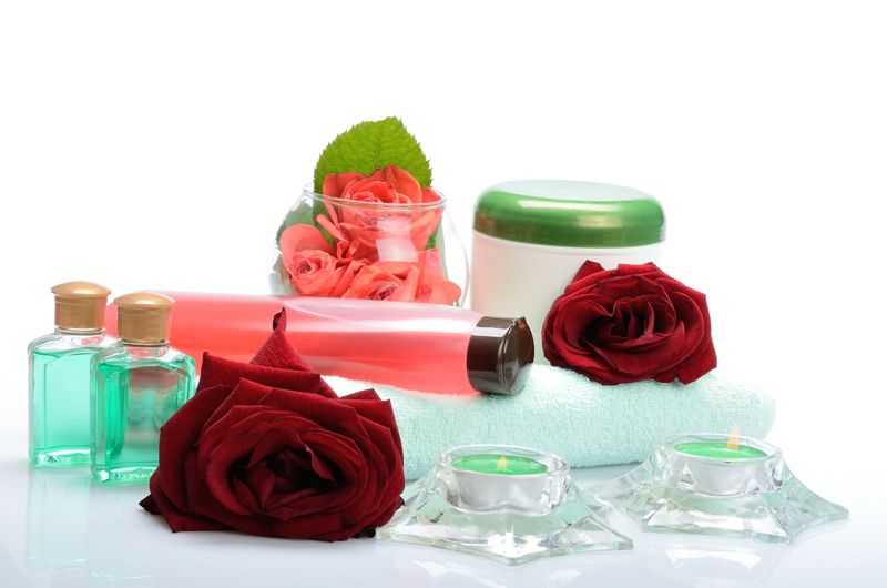 Ein Strauß Flaschen, Rosen, Kerzen und ein Handtuch auf einem Tisch