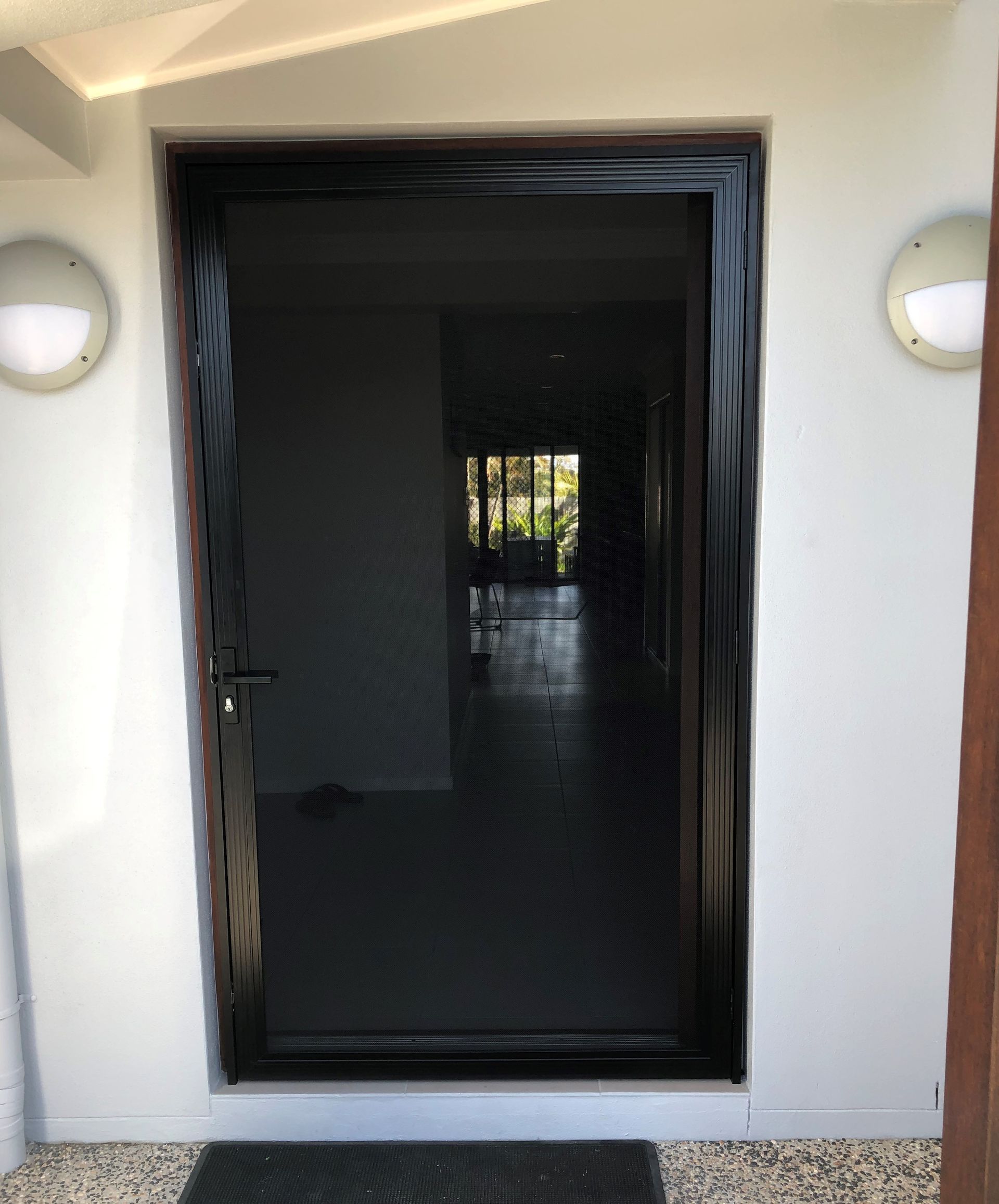 An image of a stainless steel security door with black frame on the front entrance of a house