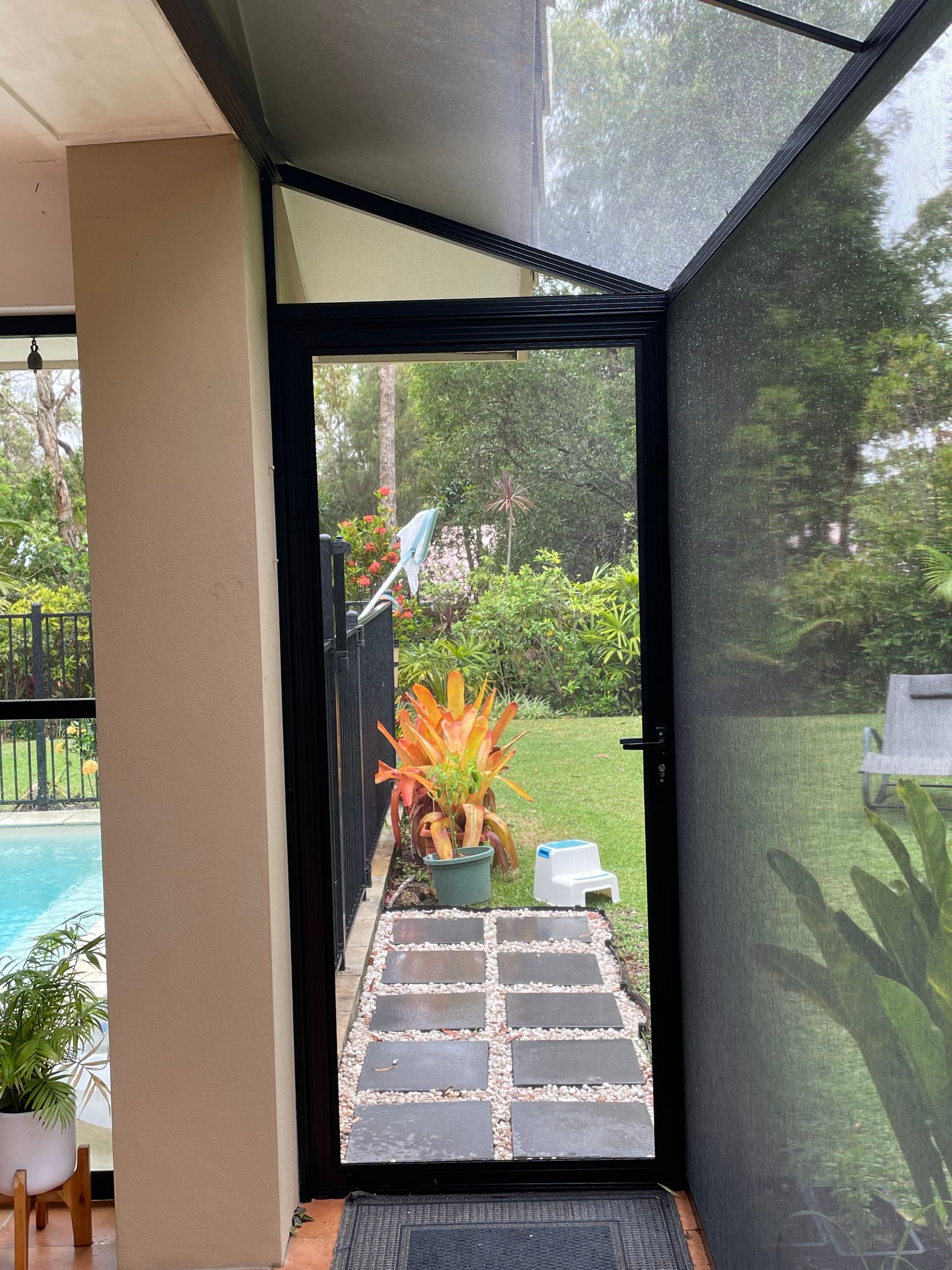 Image of  a side entry door into a stainless steel mesh patio enclosure on a house
