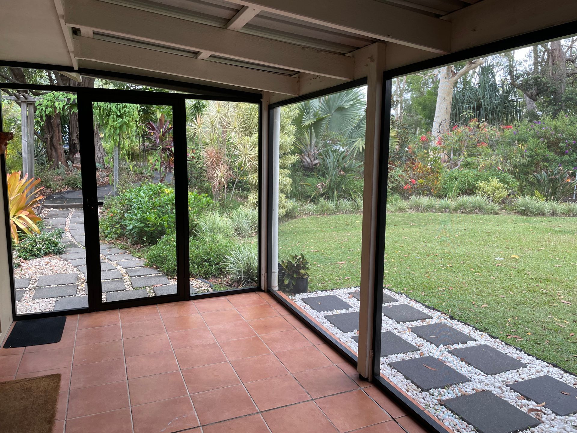 An image of a back patio of a house enclosed with insect screens and grass backyard in the background