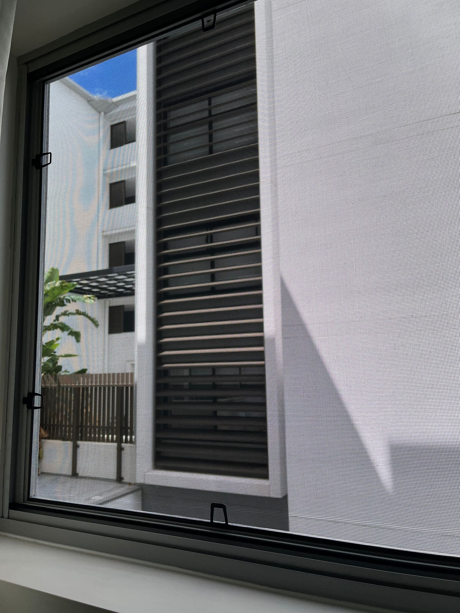A flyscreen on a bedroom window of an apartment in an apartment building