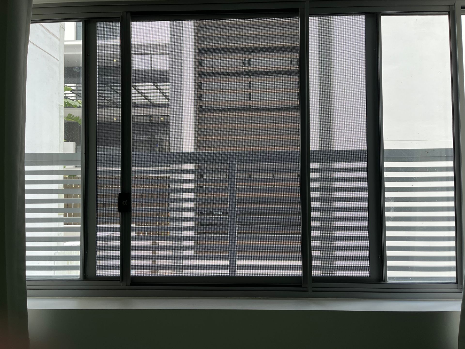 A flyscreen on a window of an apartment in an apartment building
