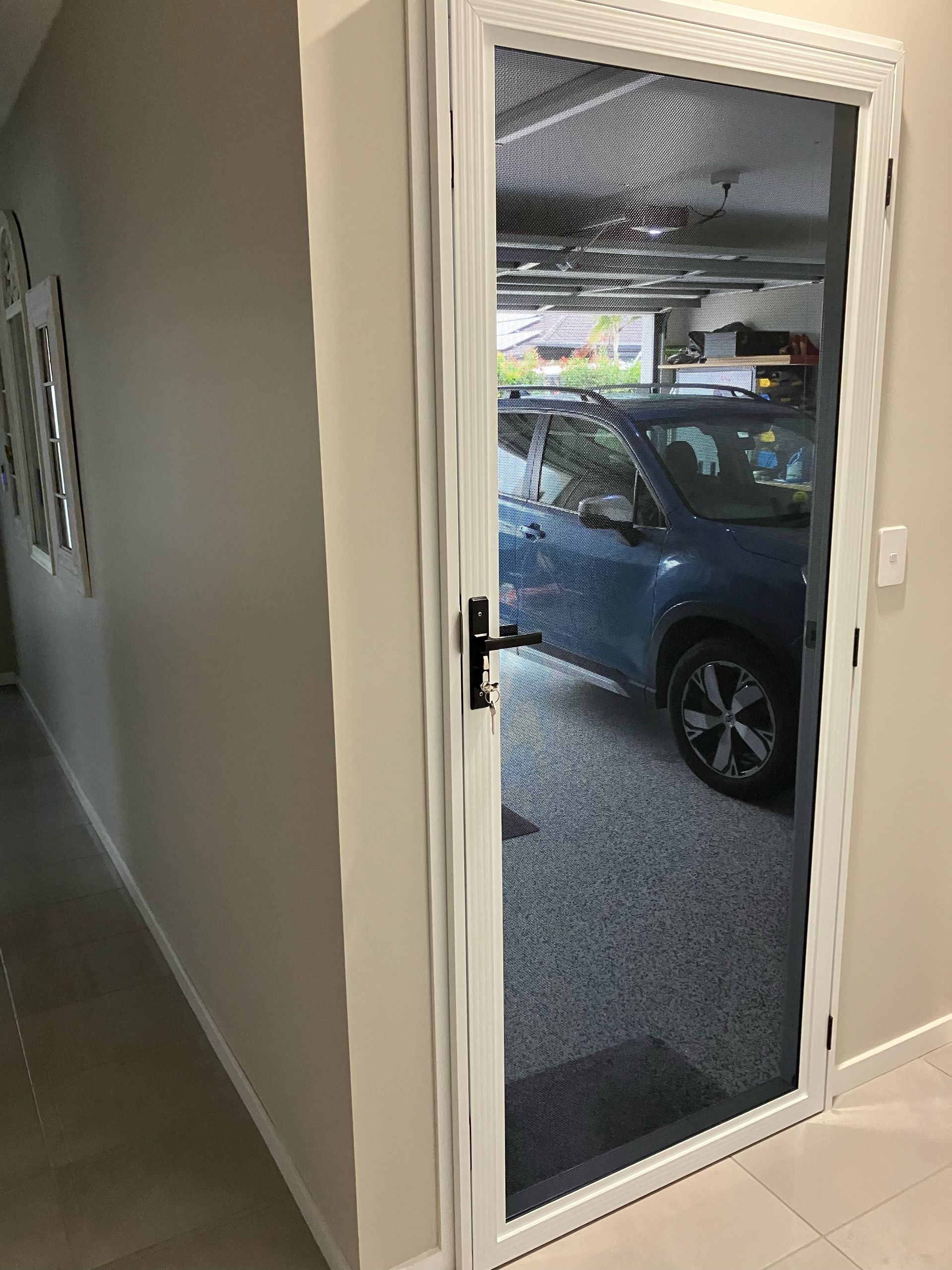A Secureview stainless steel security door leading into the garage from inside a house