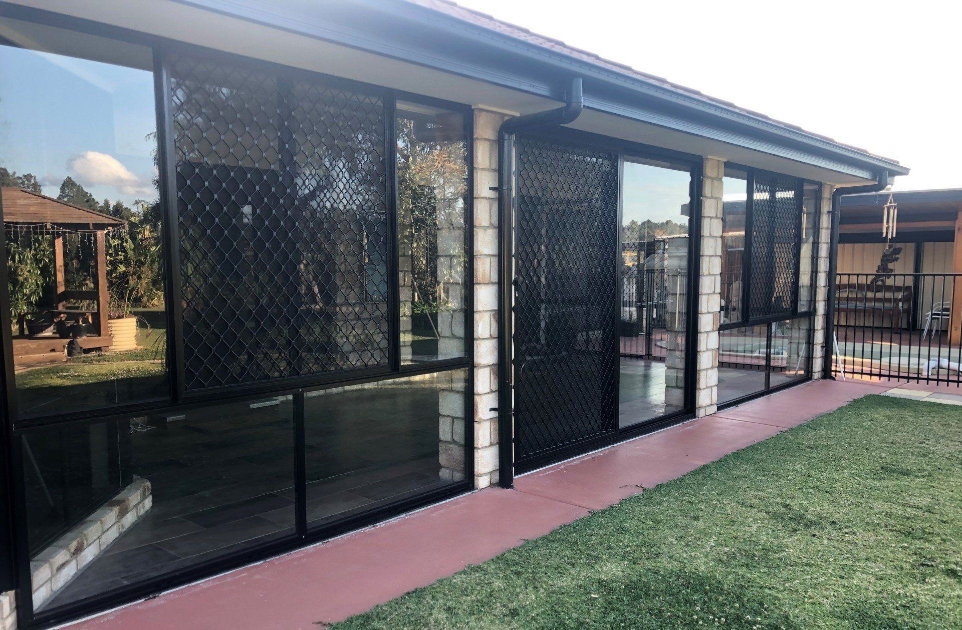 An image of black diamond grille security screens on a brick house