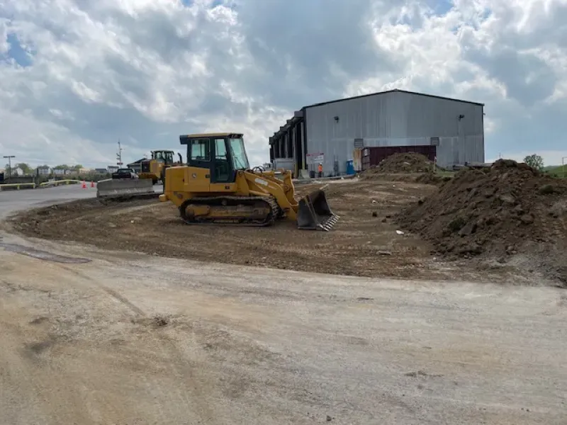 A bulldozer is sitting in a dirt field in front of a building.