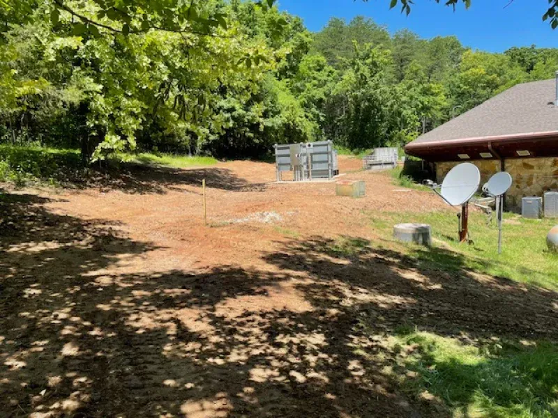 A dirt road leading to a house with satellite dishes in front of it.