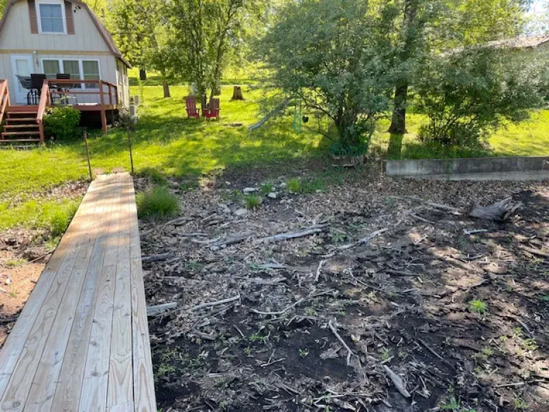 There is a wooden dock leading to a house in the background.