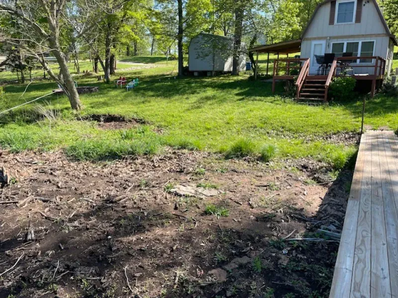 A house is sitting on top of a lush green field next to a wooden deck.