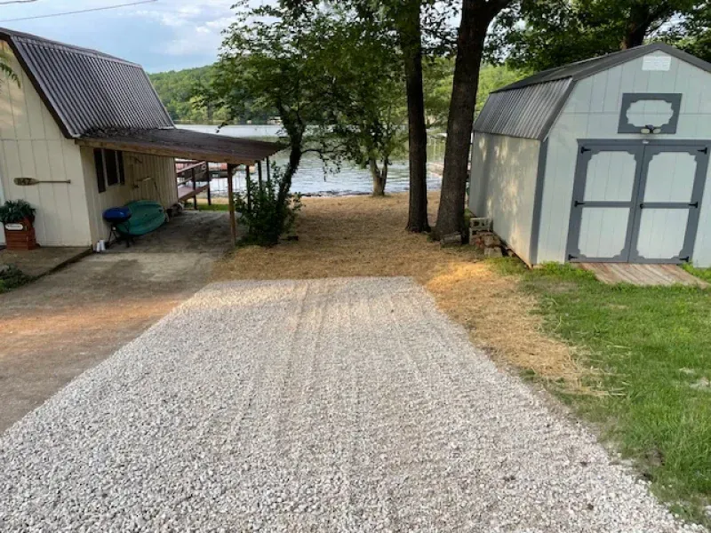 A gravel driveway leading to a shed next to a house.