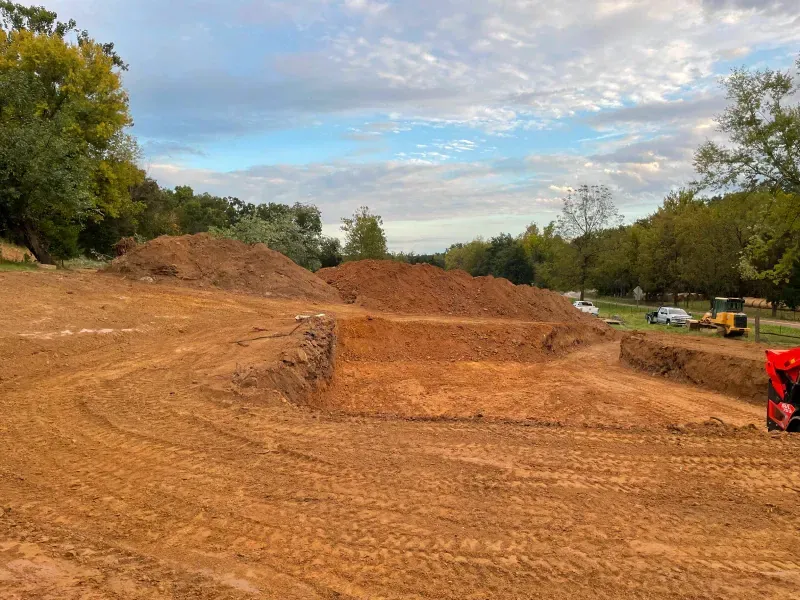 A large pile of dirt is sitting in the middle of a dirt field.