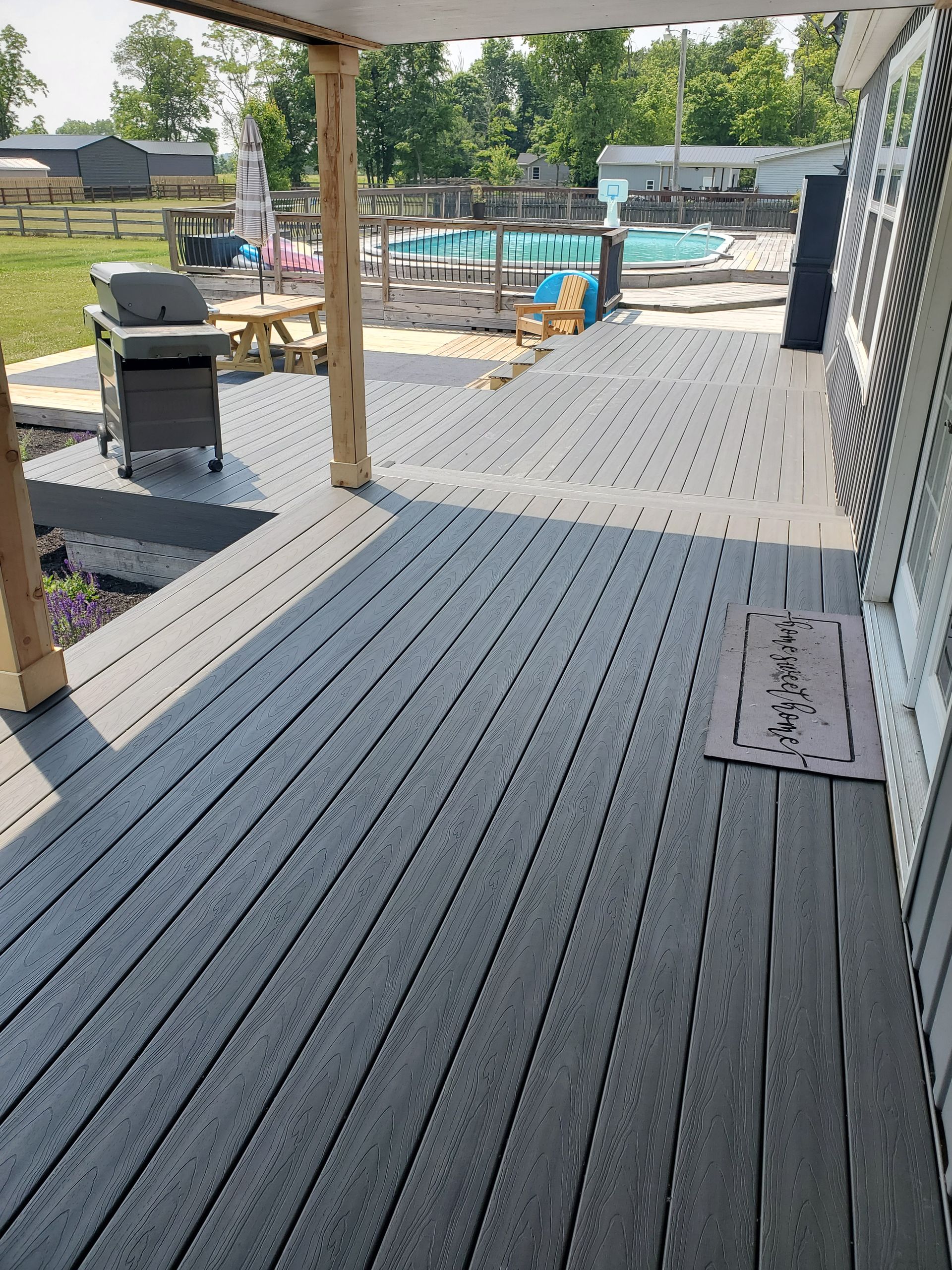 Wooden deck with grill, leading to a pool area and playground.