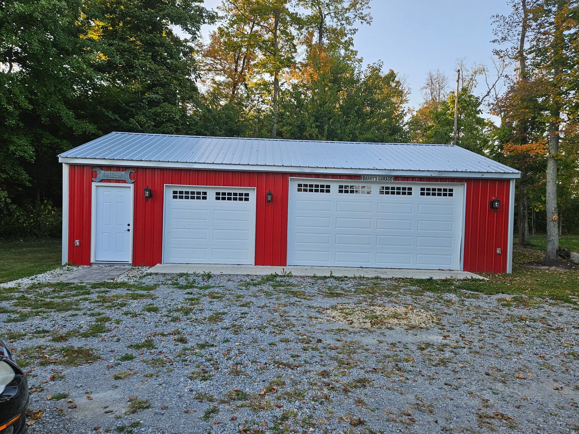 Red metal garage with white doors and a metal roof.