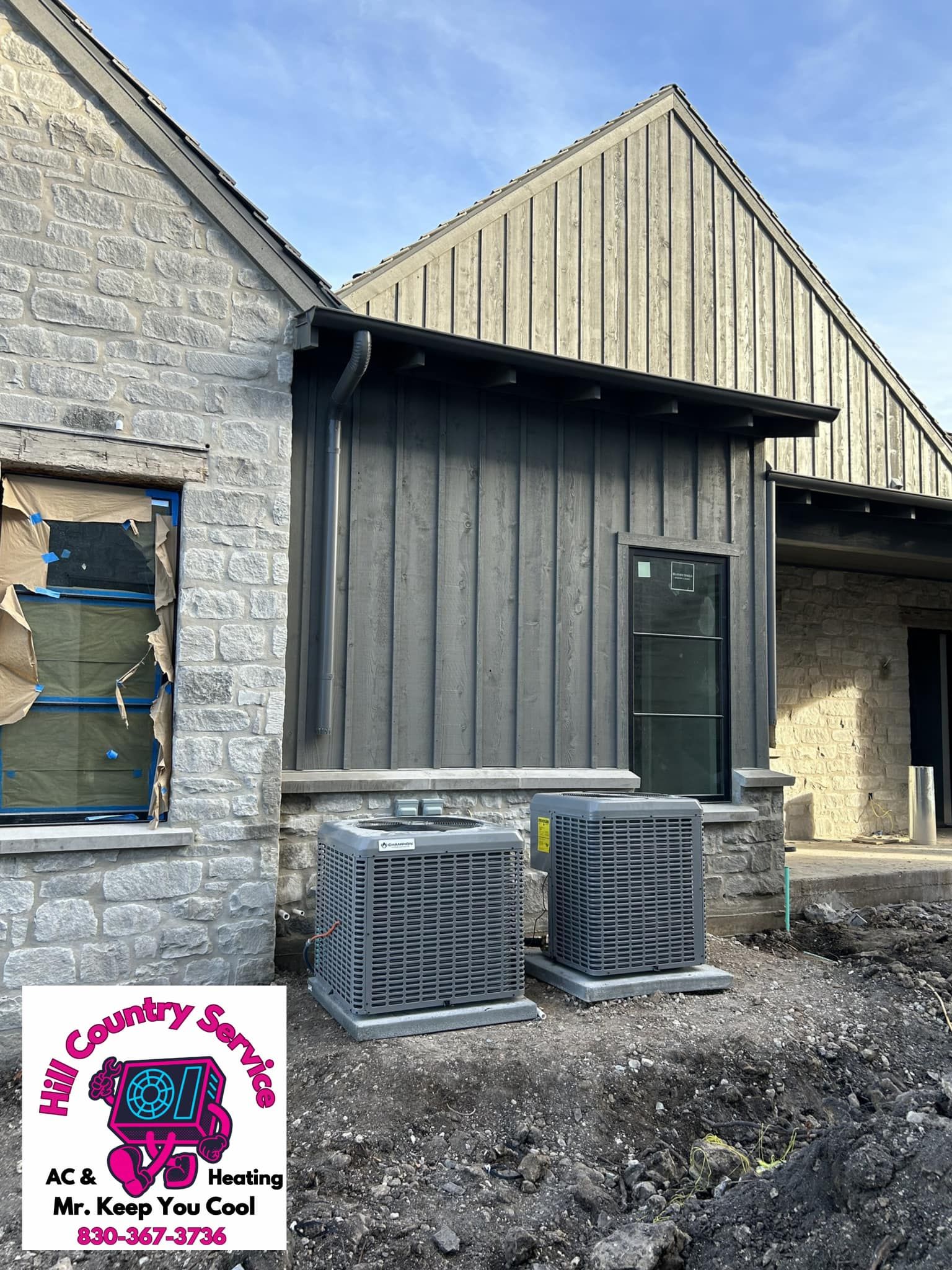 A brick building with a metal siding and two air conditioners on the side of it.