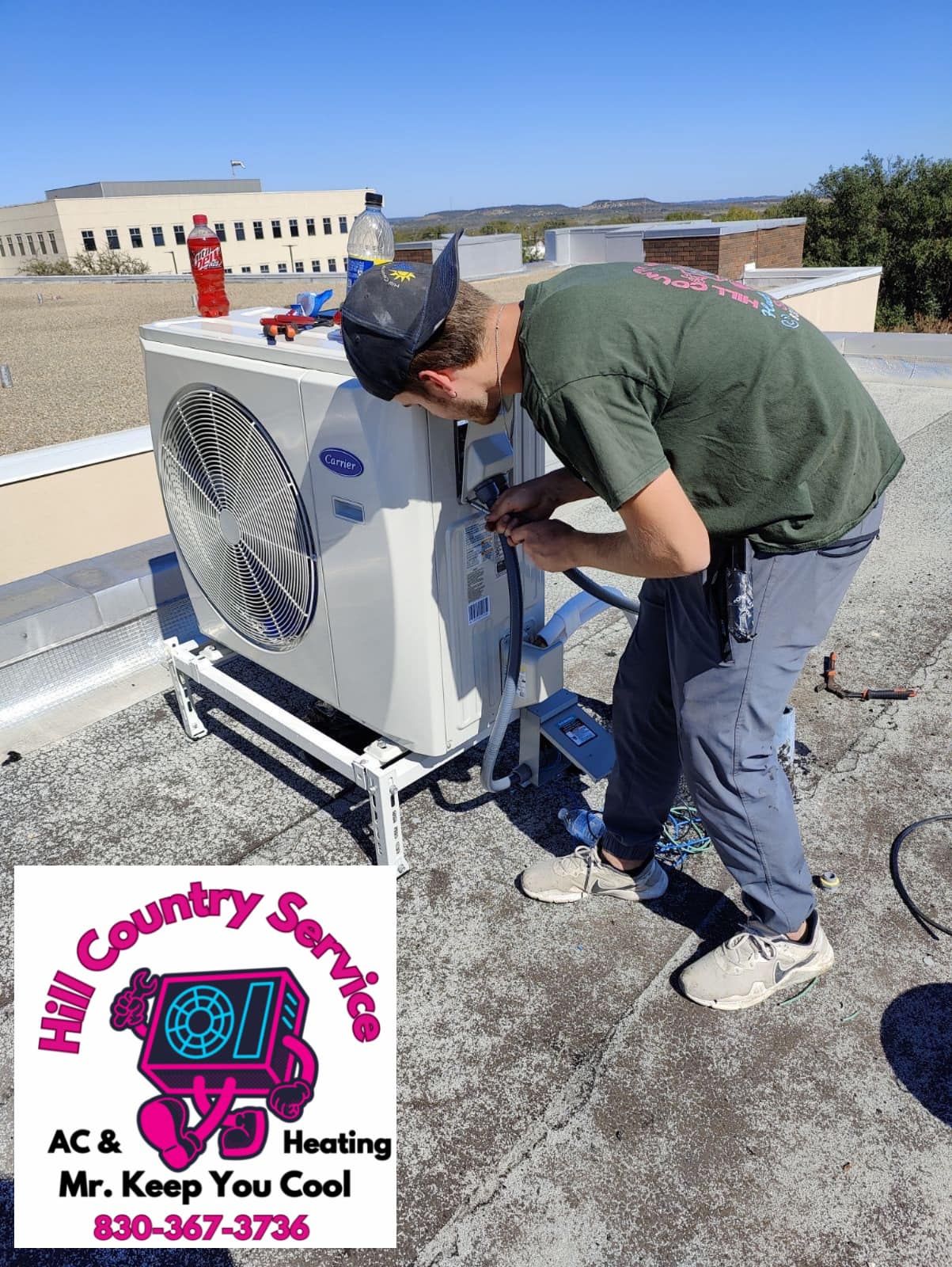 A man is working on an air conditioner on the roof of a building.