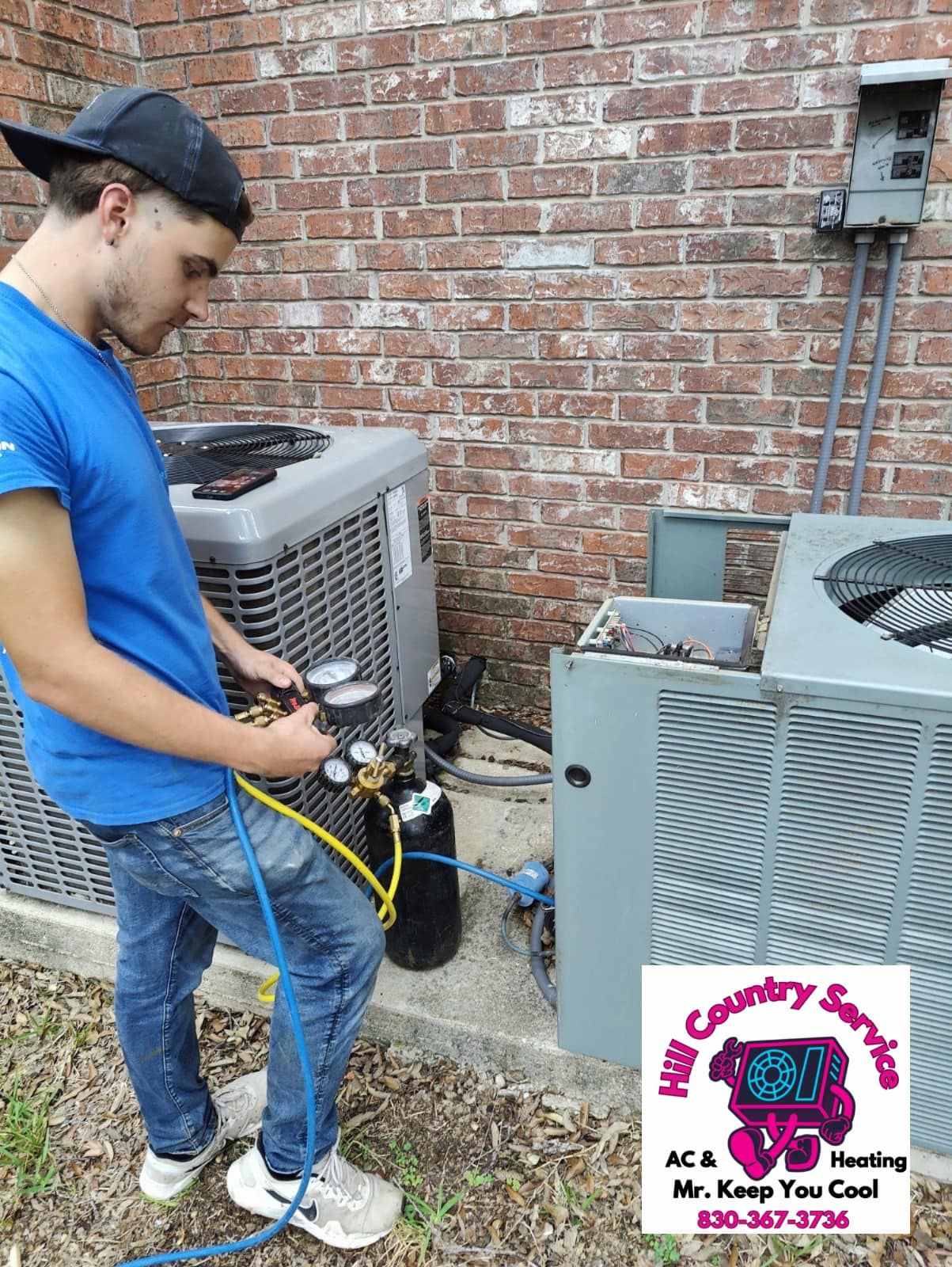 A man is working on an air conditioner outside of a brick building.