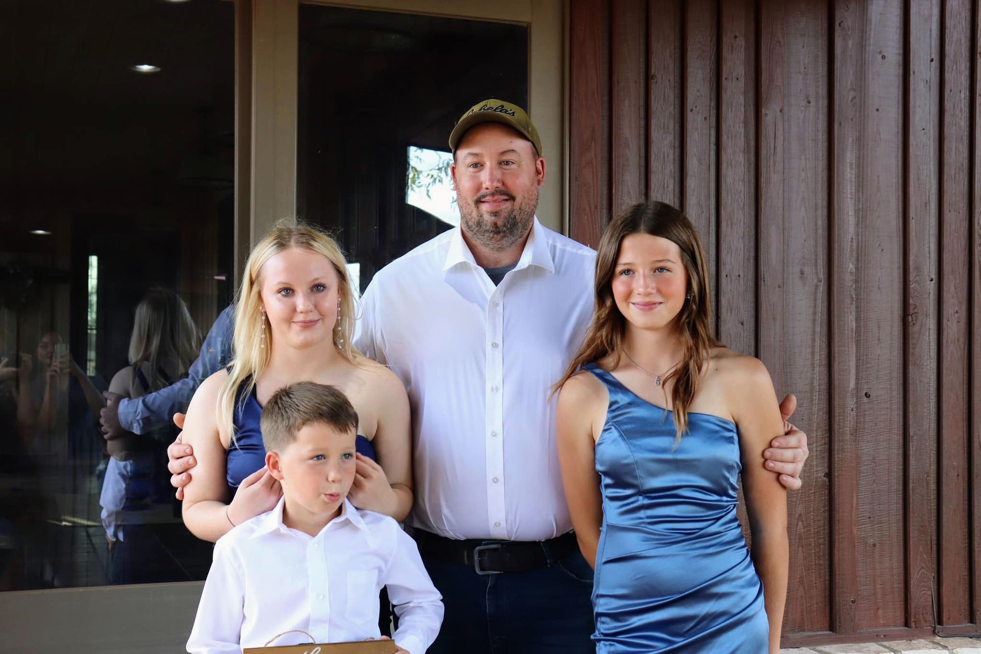 A man and three children are posing for a picture in front of a building.