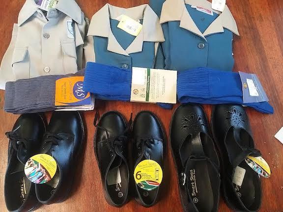 A bunch of school uniforms and shoes on a table