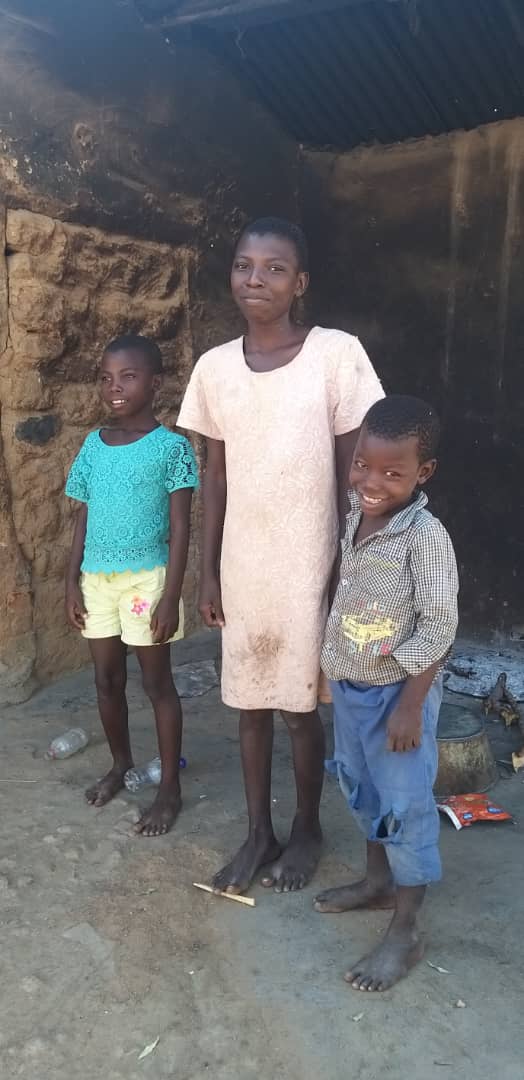A group of children are standing next to each other in front of a building.