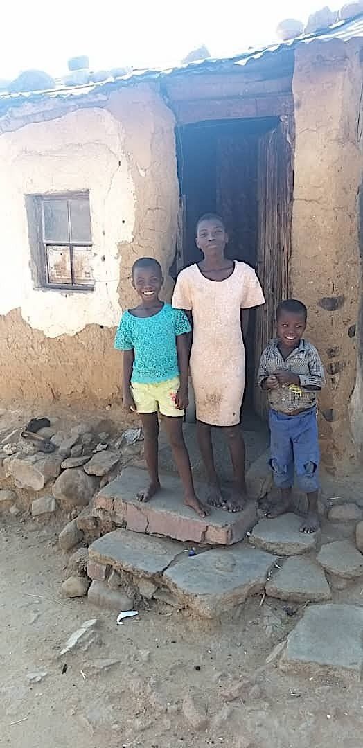 A woman and two children are standing in front of a building.