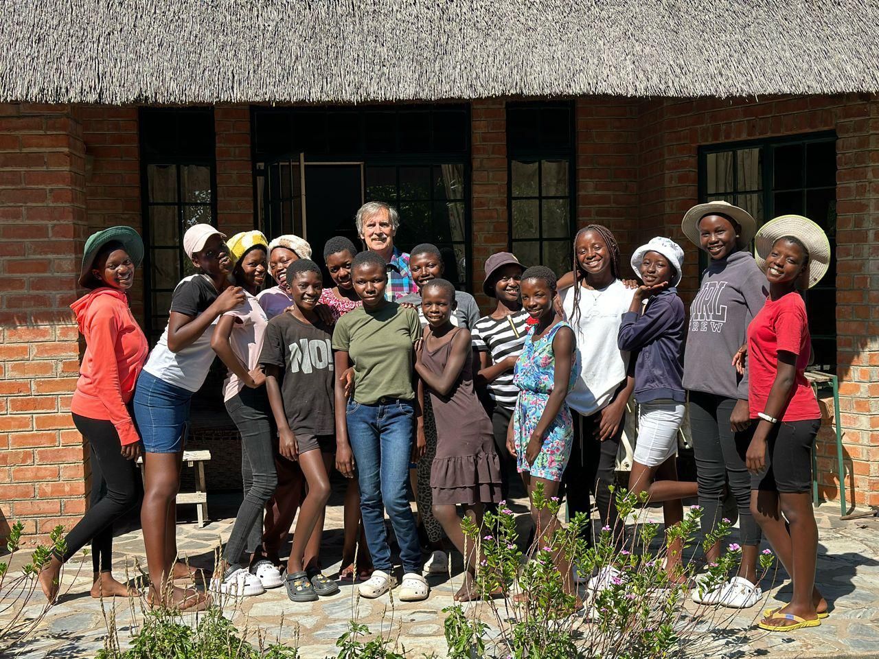 A group of young people are posing for a picture in front of a brick building.