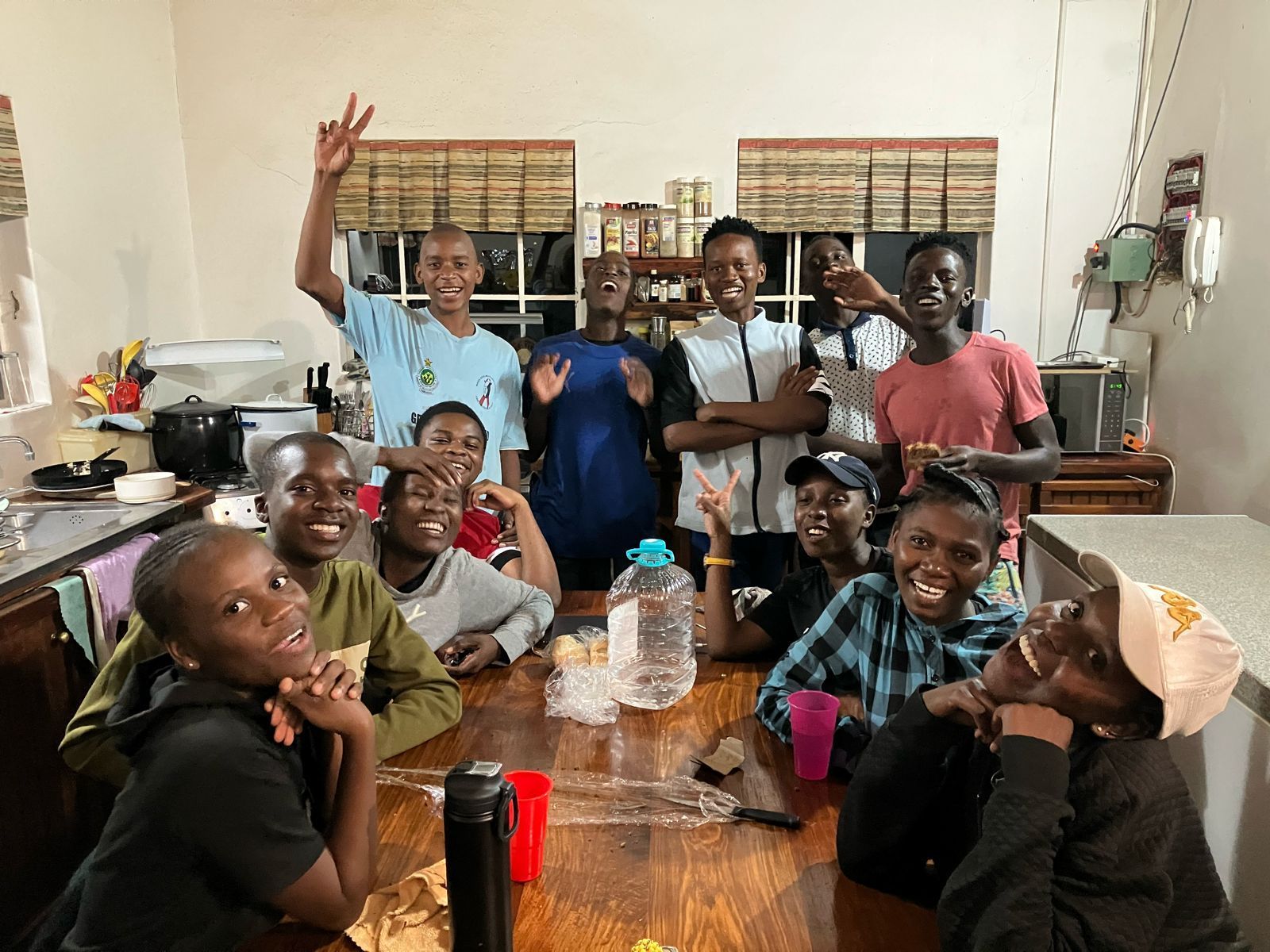 A group of children are sitting around a table in a kitchen.