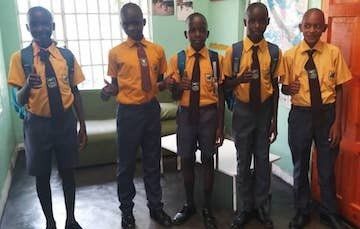 A group of young men in school uniforms and ties are standing next to each other in a room.