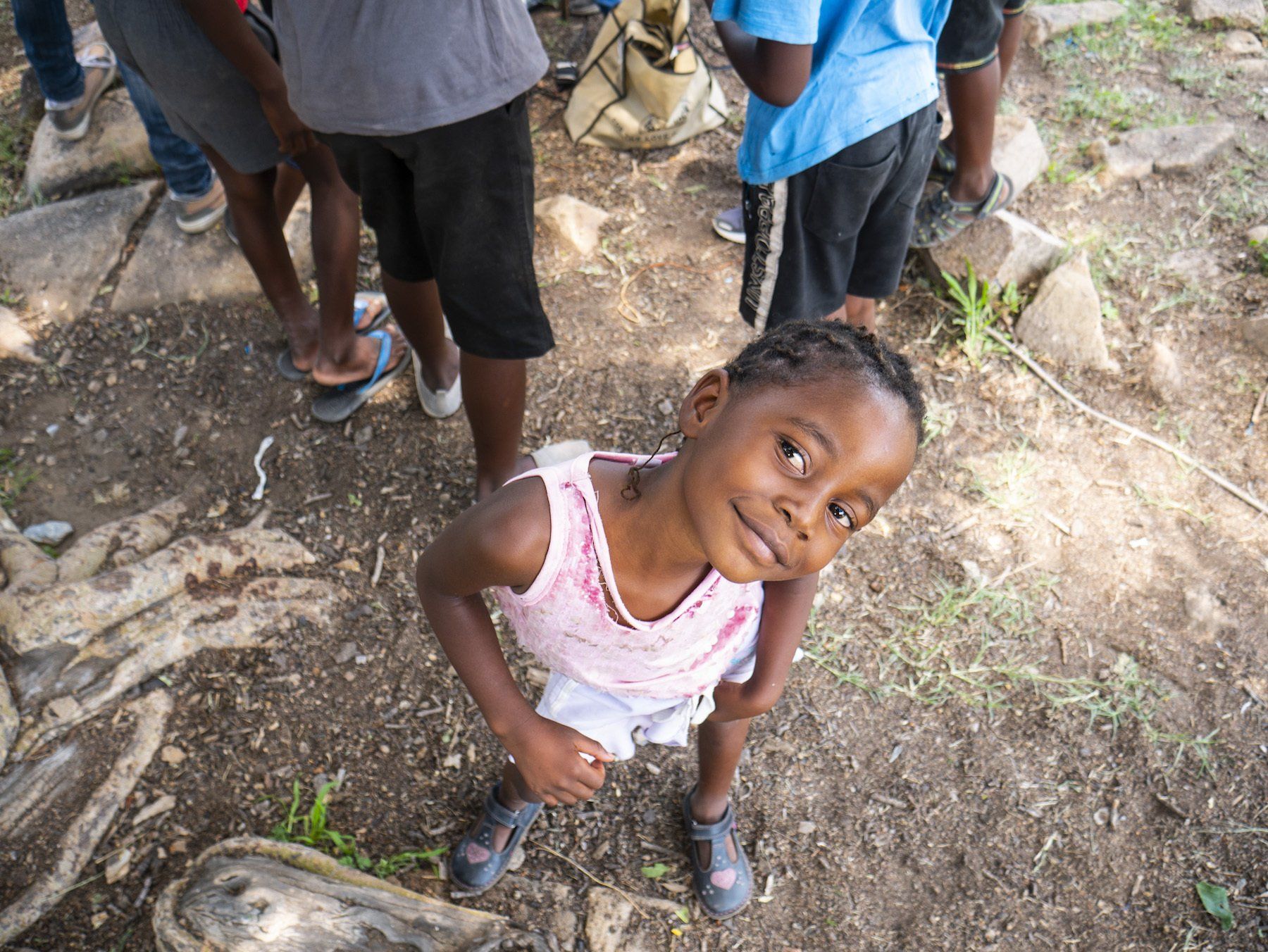A little girl is standing on the ground looking up at the camera.