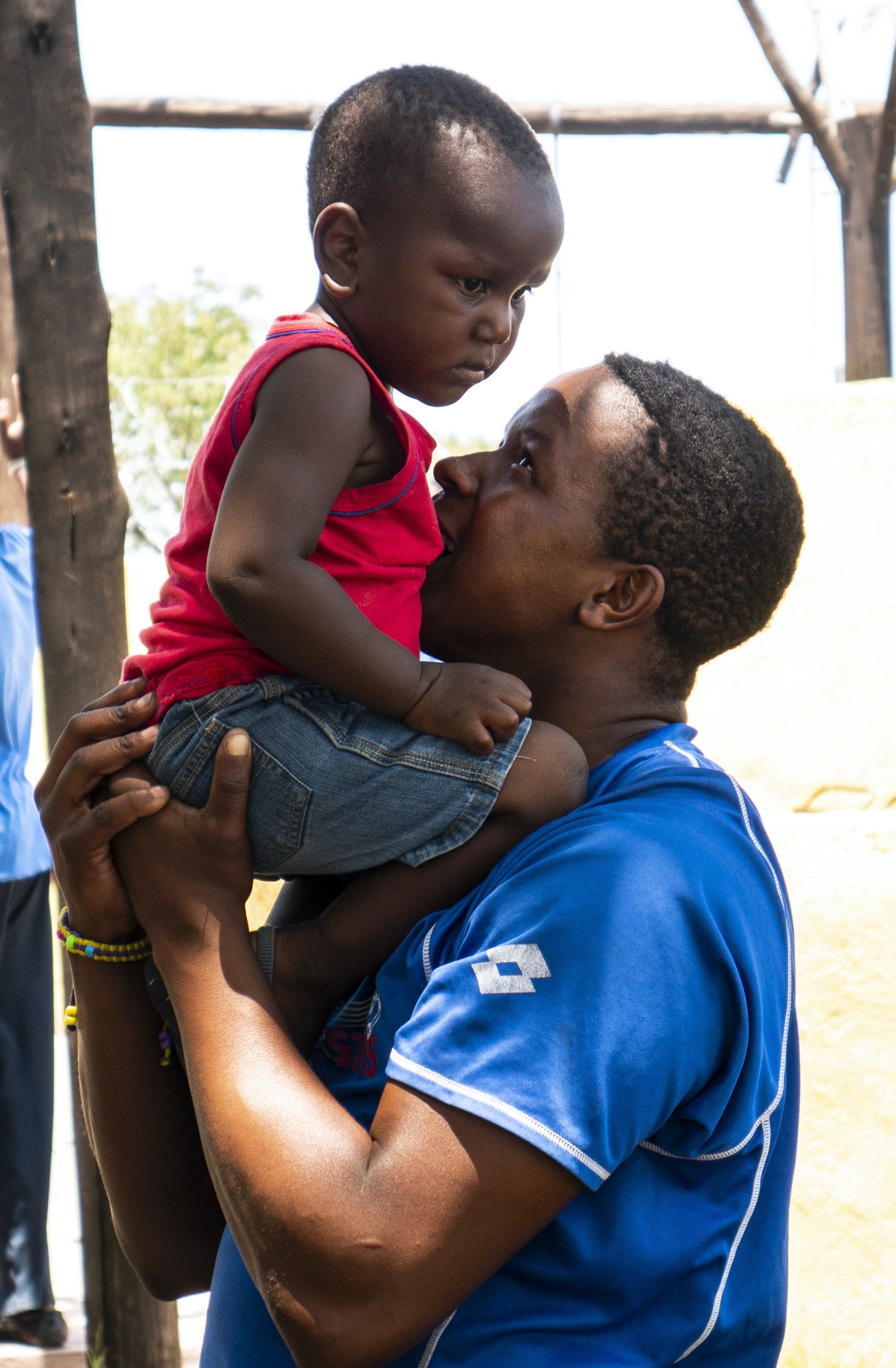 A man in a blue shirt is holding a small child in his arms.