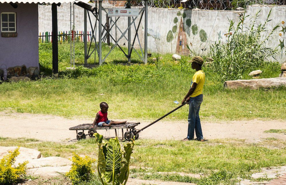 A man is pulling a cart with a child on it.