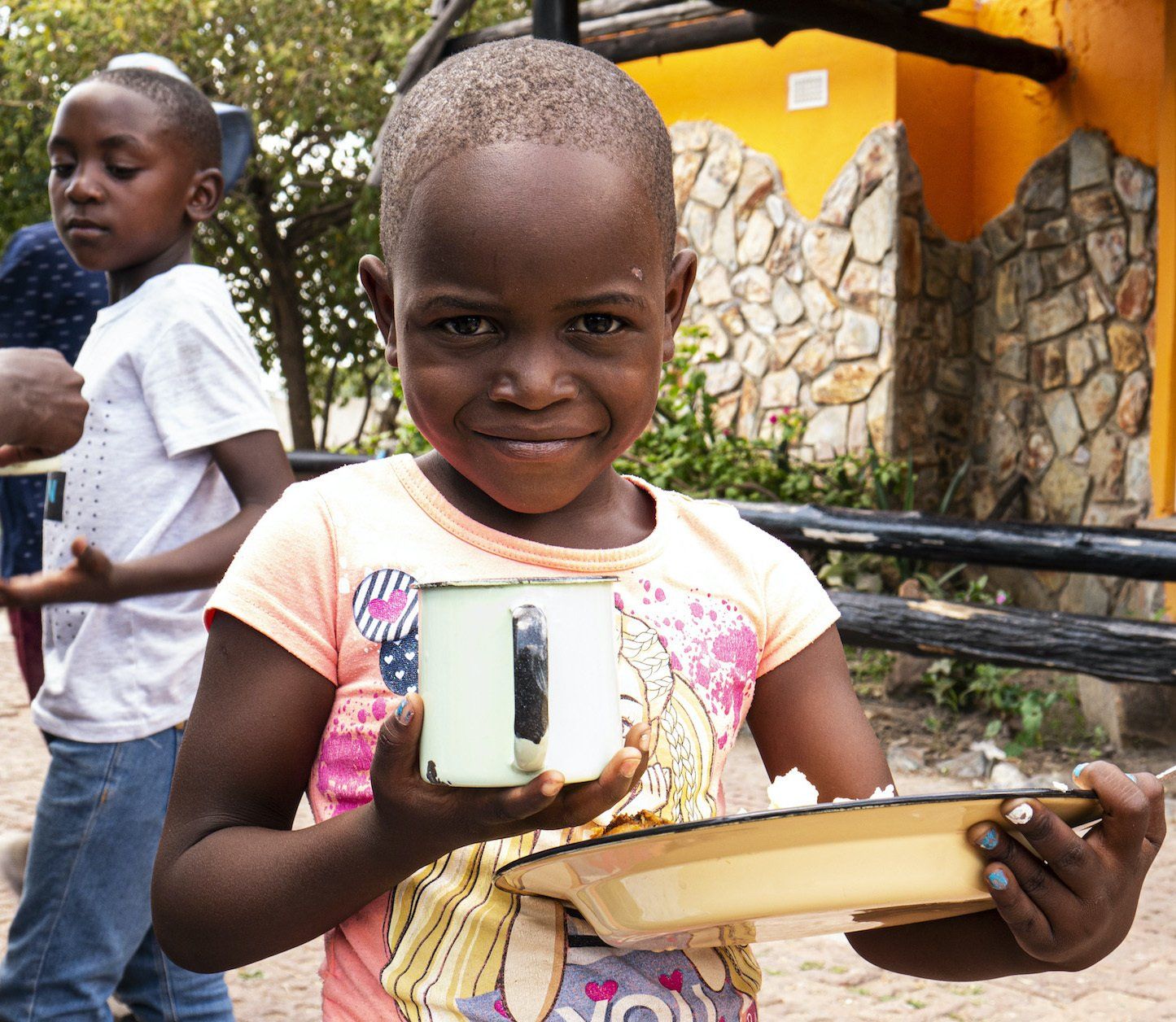 A little girl is holding a cup and a tray