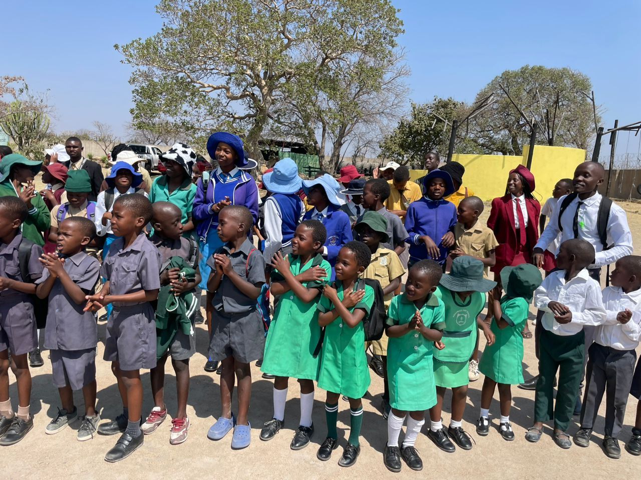 A group of children are standing in a line with their hands on their chests
